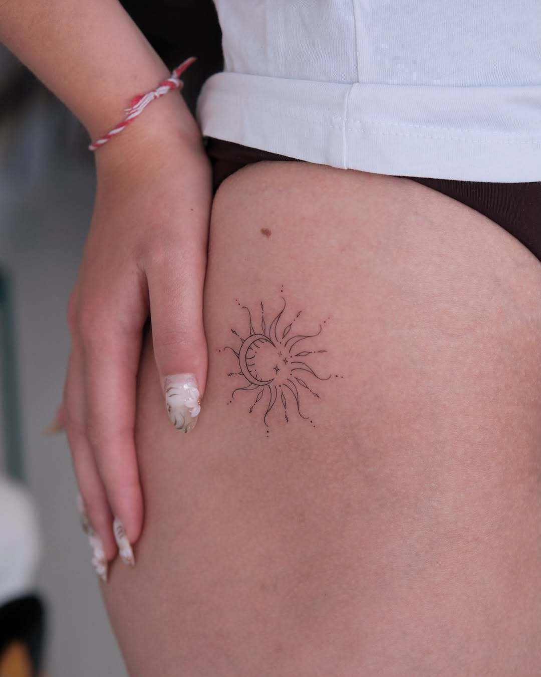 Sun and moon fine line tattoo on the thigh by Göksu