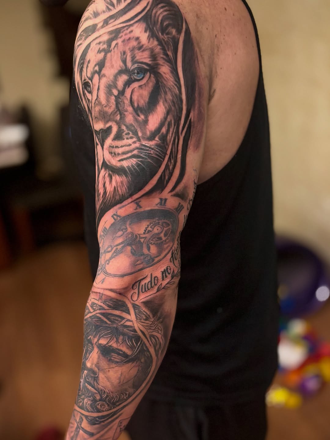 Lion and Jesus Christ portrait Chicano tattoo on the upper arm by Mauricio gois