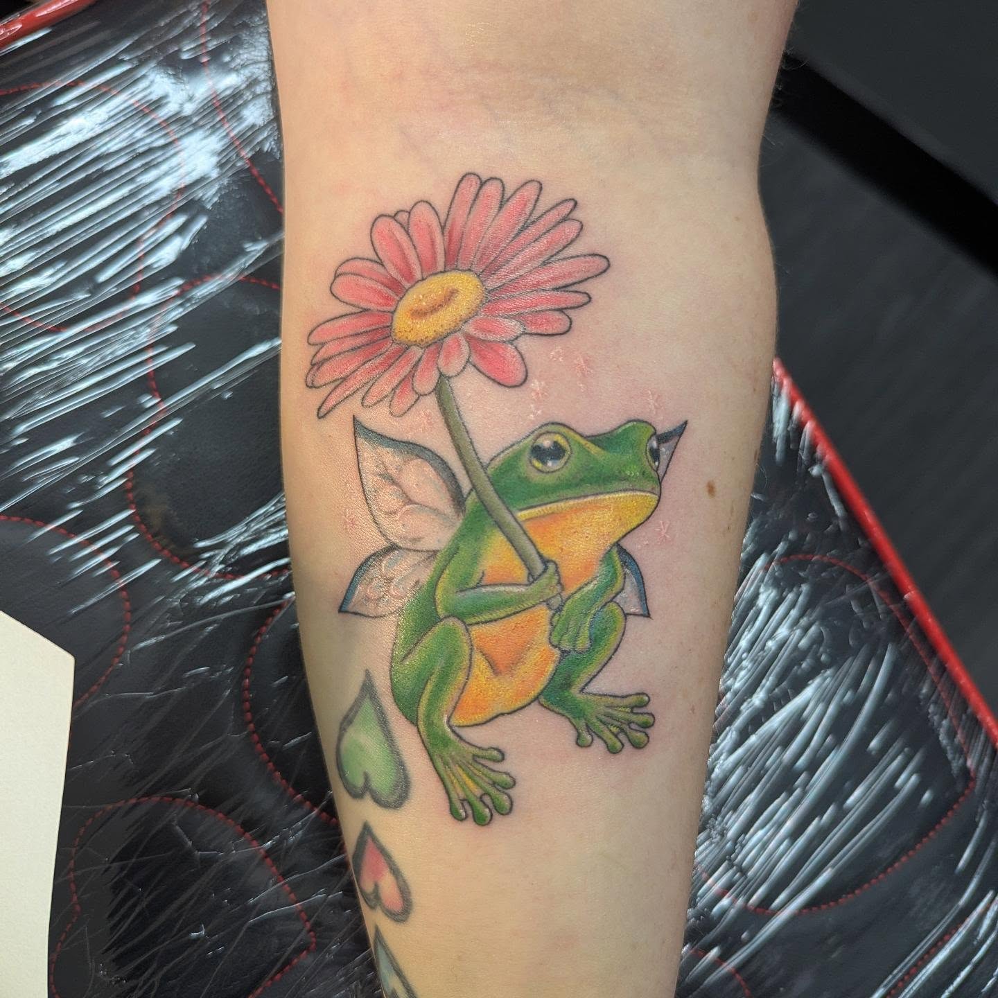 Frog with flower new school tattoo on the forearm by Hannah Hayes, Livonia, Michigan