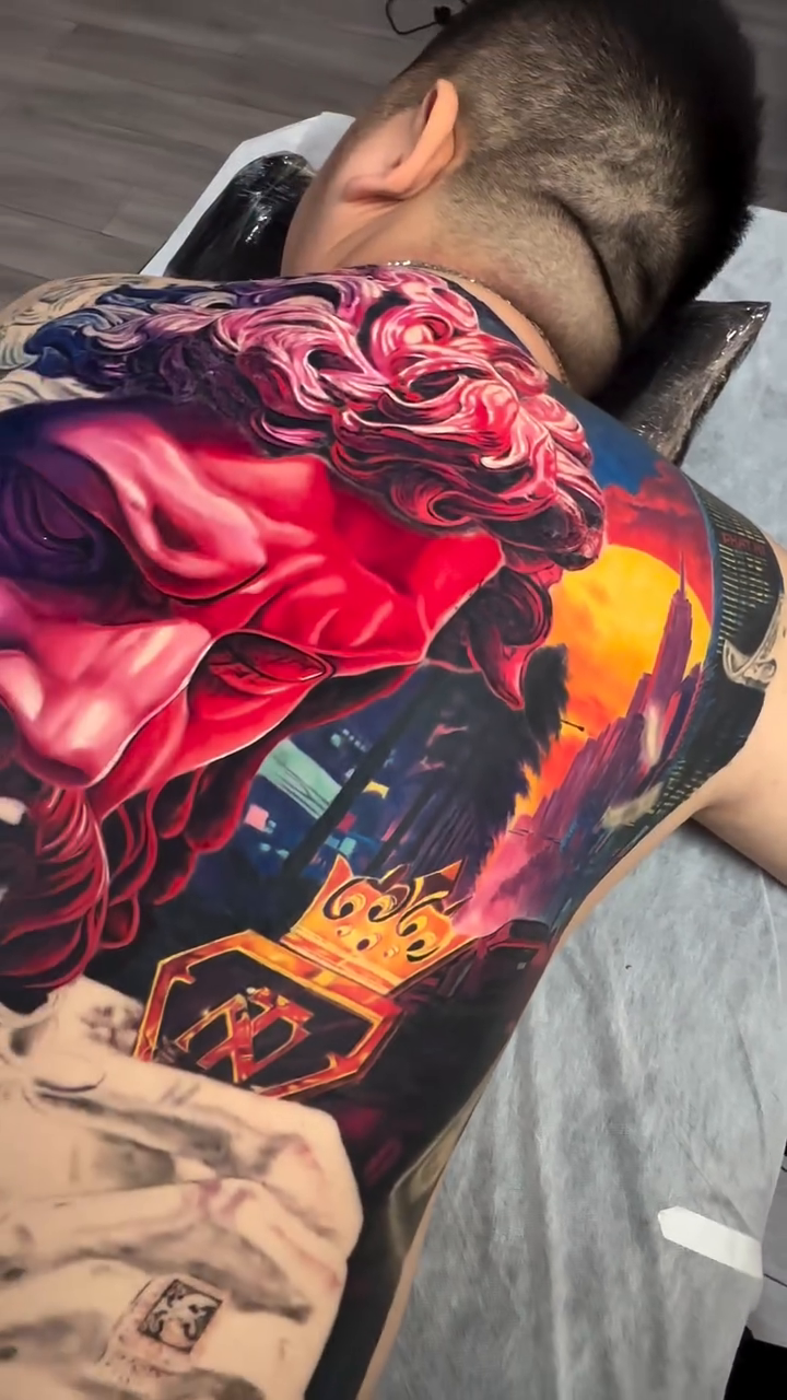 Mythological figure with crown and cityscape surrealism tattoo on the back by Bình Nguyễn