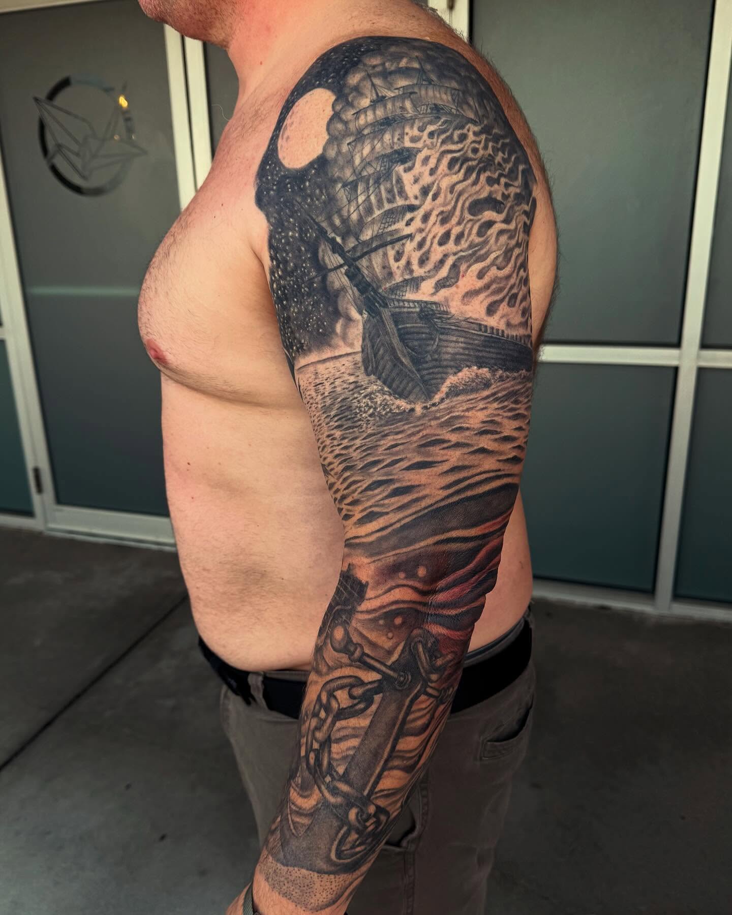 Ship sailing through storm realism tattoo on the upper arm by Jesse Gray