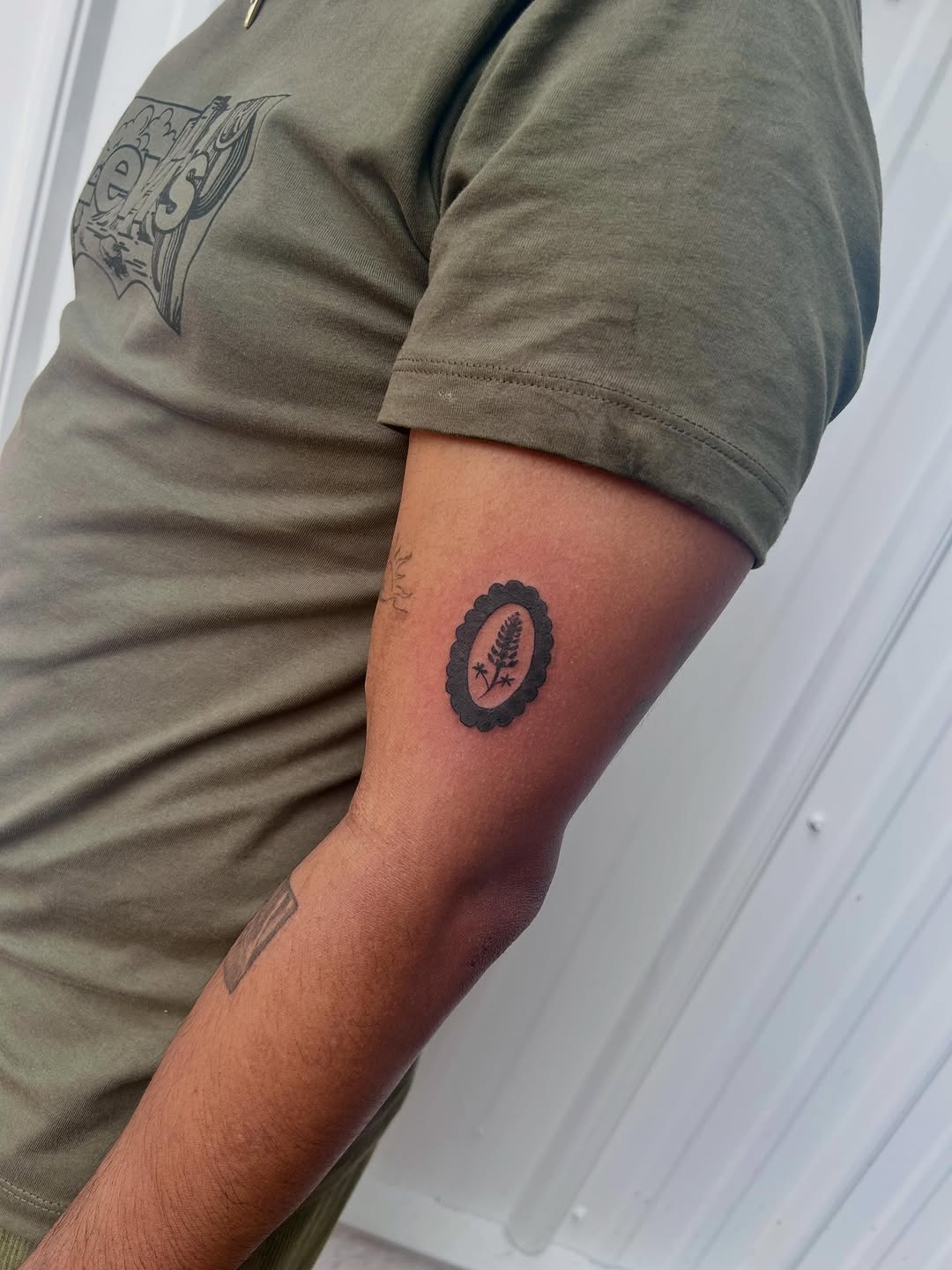 Fern in oval frame minimalist tattoo on the forearm by Miss Katie