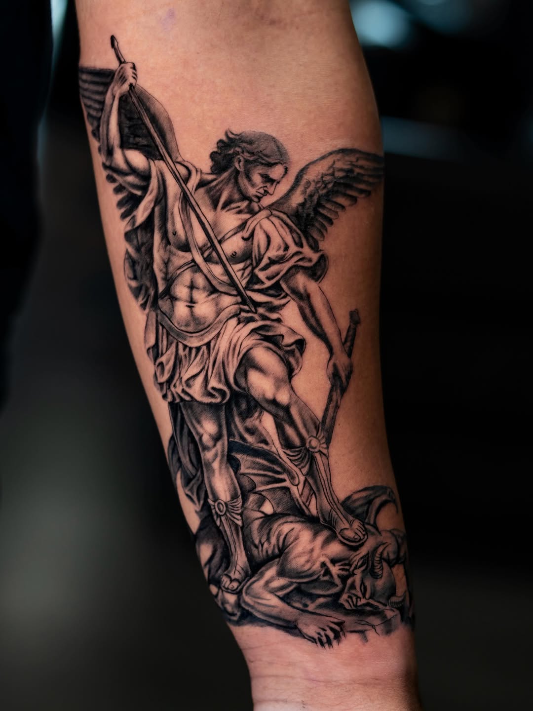 Archangel Michael defeating a demon realism tattoo on the forearm by Charlotte Tattoo Artist