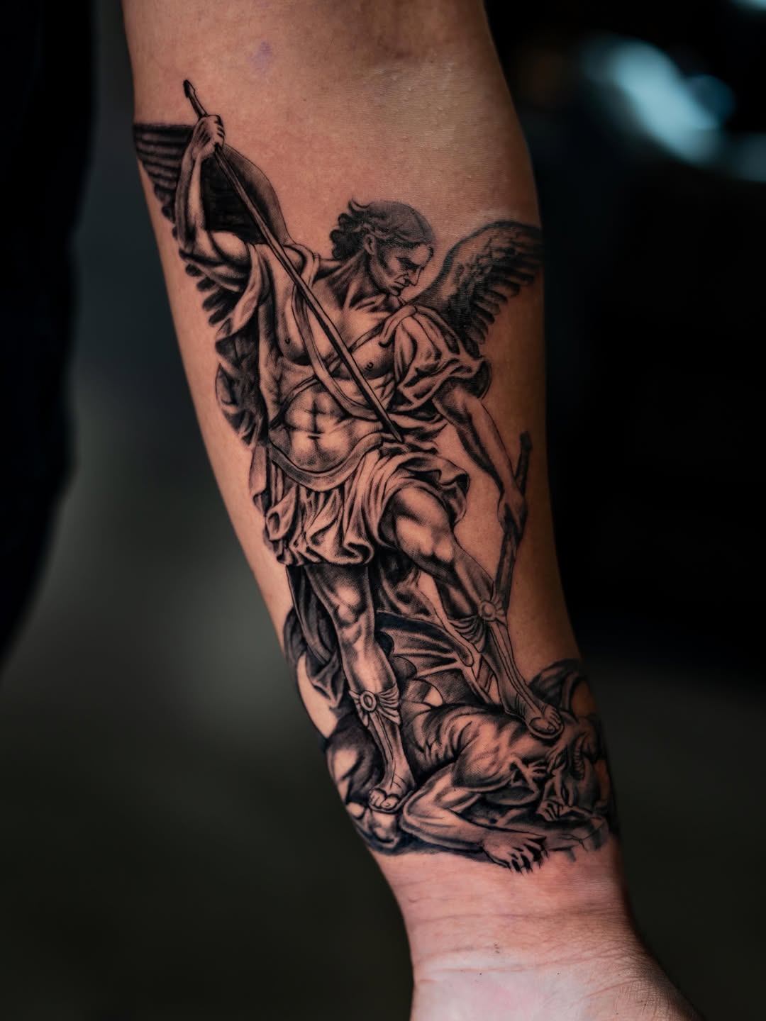 Archangel Michael defeating a demon realism tattoo on the forearm by Charlotte Tattoo Artist