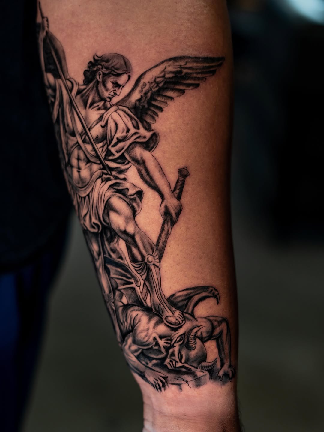 Archangel Michael battling a demon realism tattoo on the forearm by Charlotte Tattoo Artist