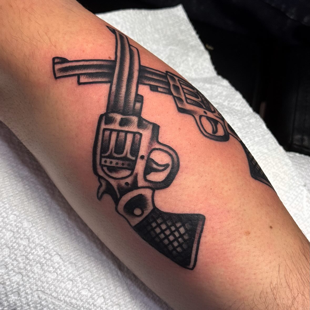 Revolver black and grey tattoo on the forearm by Larry Love