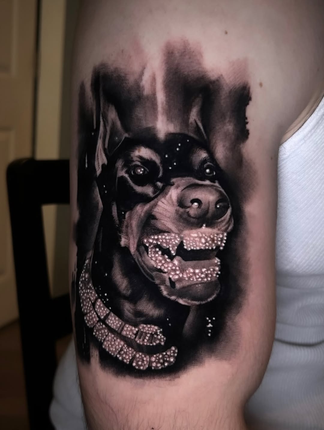 Doberman with diamond grill and necklace realism tattoo on the forearm by Dallas Corsmeier