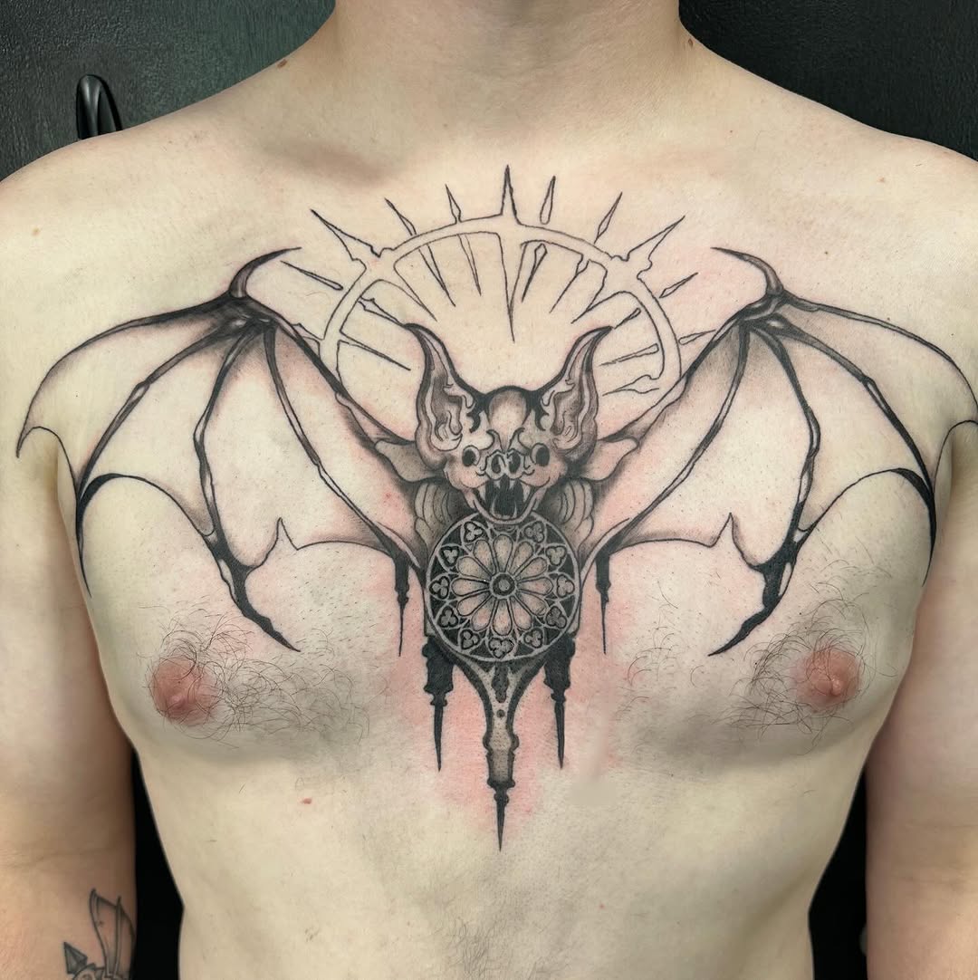 Bat with gothic rose window blackwork tattoo on the chest by Mika'la Berry
