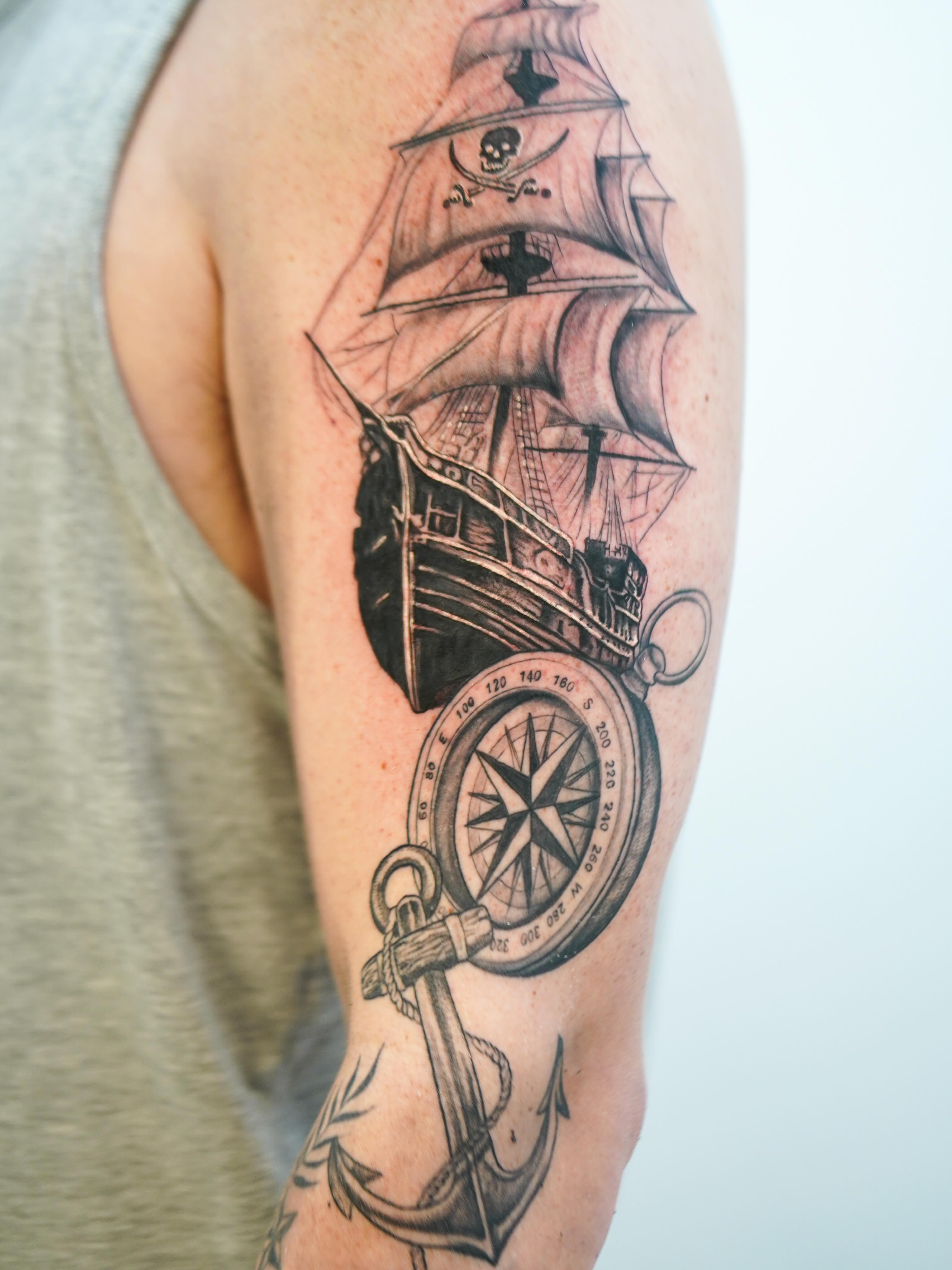 Pirate ship and compass black and grey tattoo on the forearm by Skylar
