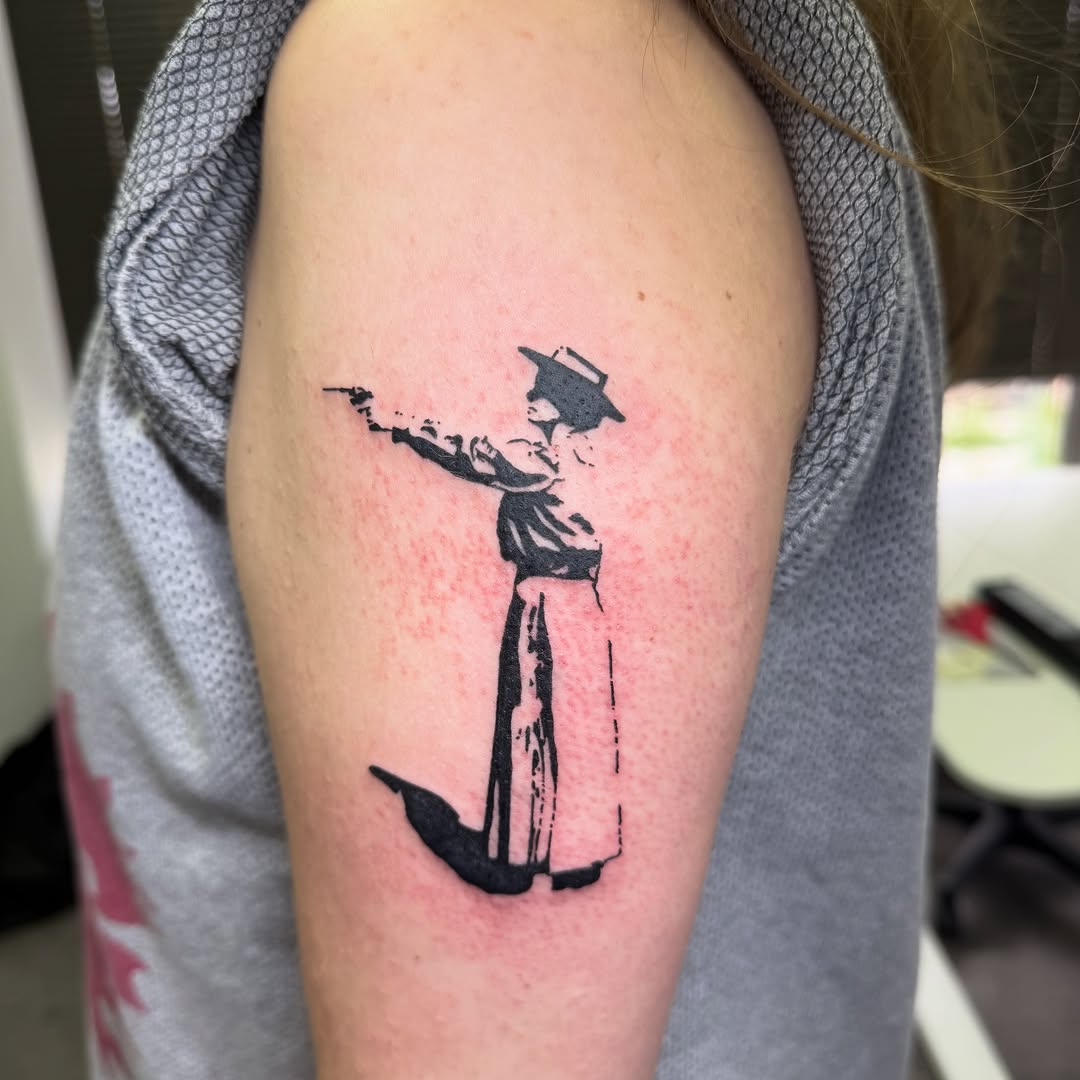 Woman with gun minimalist tattoo on the upper arm by 🌸Blossom🌸
