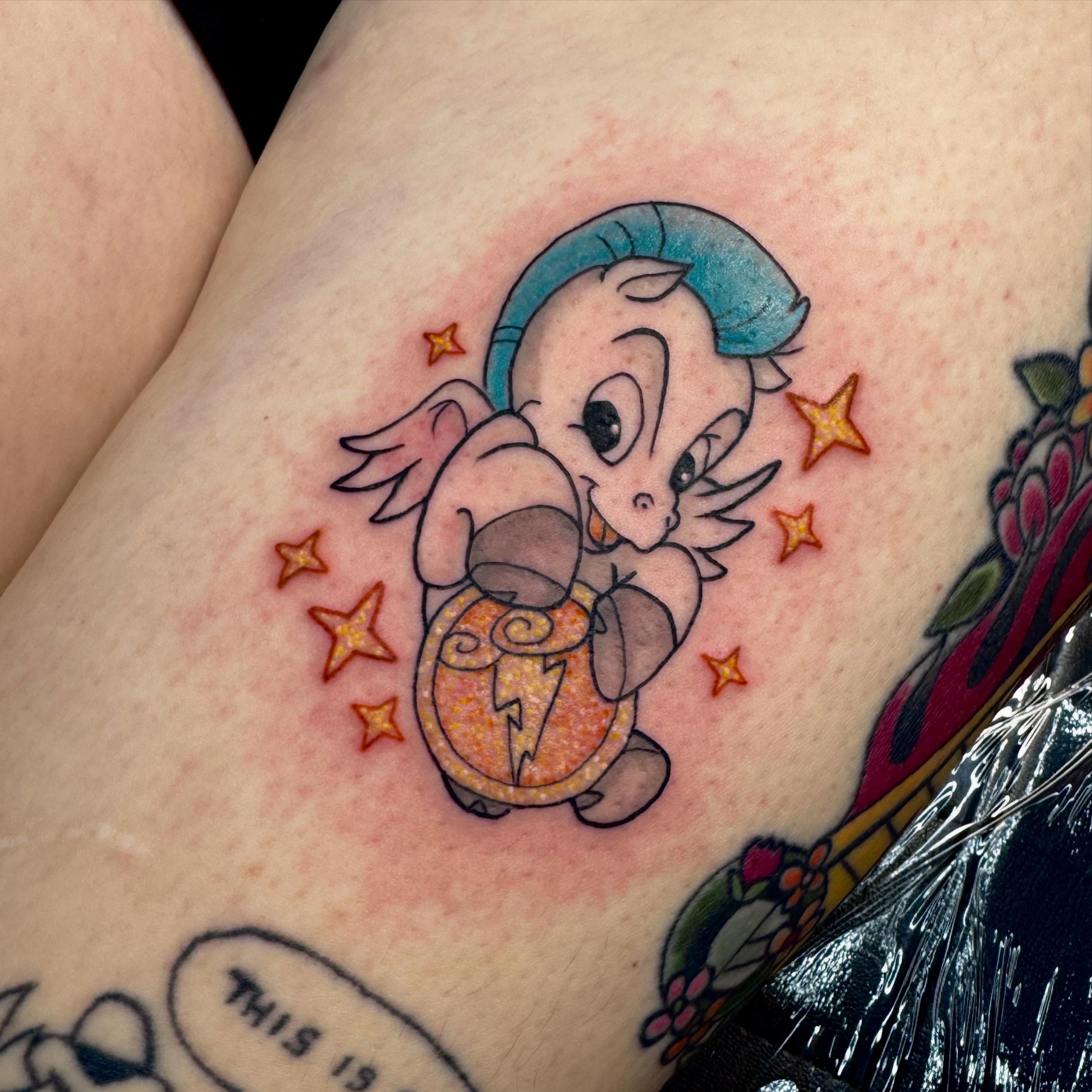 Baby character with shield new school tattoo on the forearm by Jada Reynolds