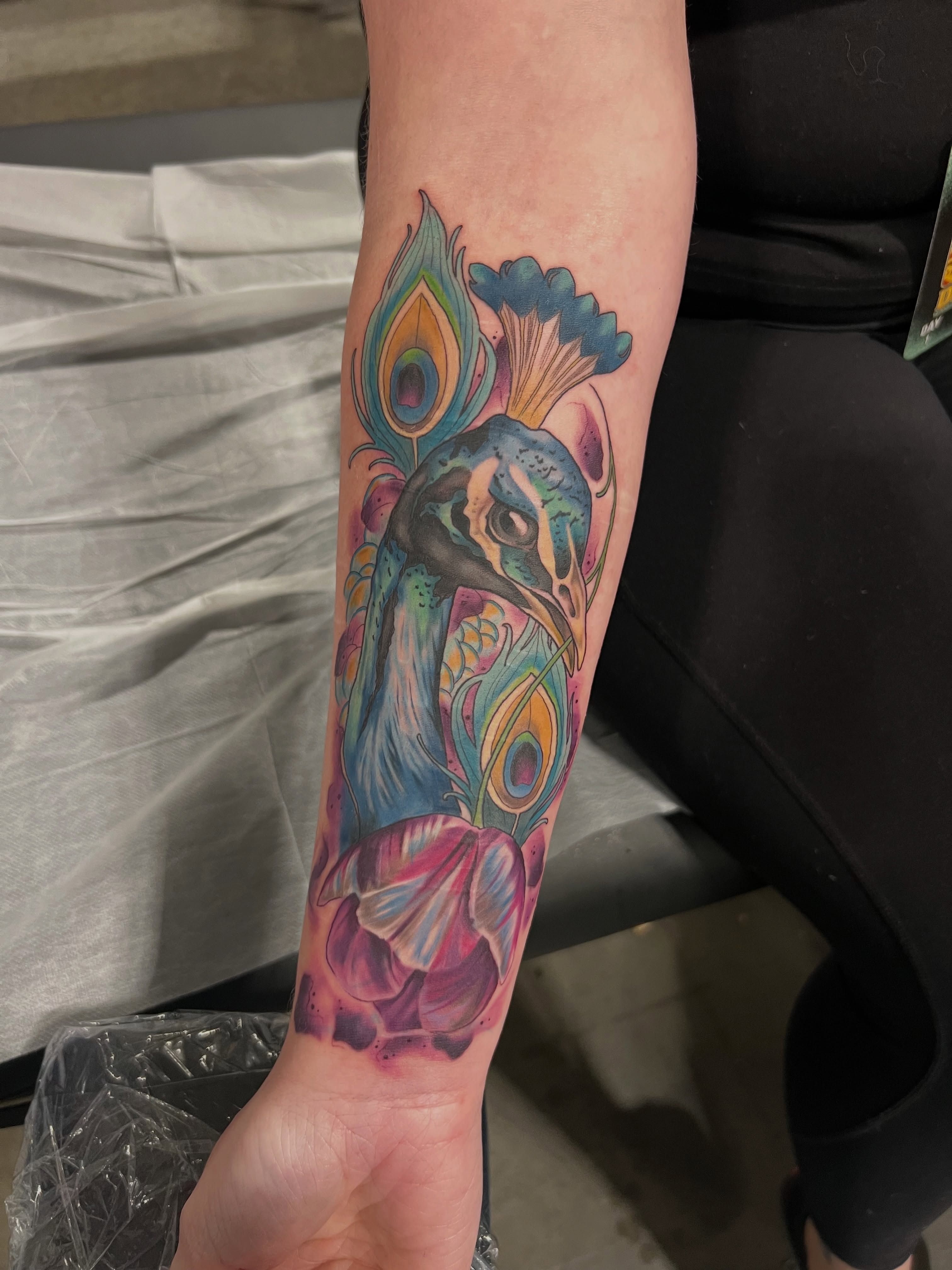 Peacock new school tattoo on the forearm by Belle Halverson