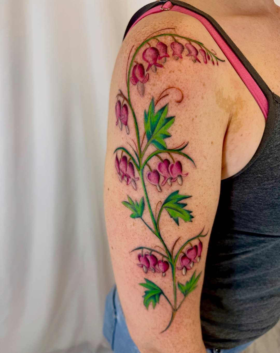Bleeding heart flowers realism tattoo on the upper arm by Jerry Thomas