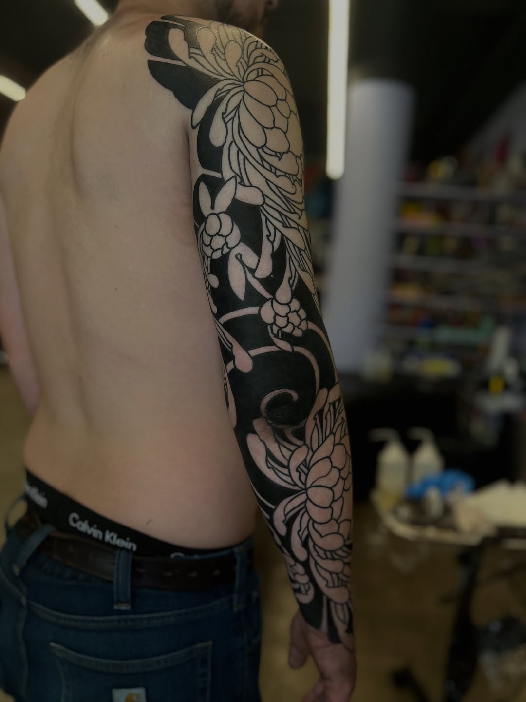 Chrysanthemums and leaves Japanese tattoo on the upper arm by Kaichi Fujita, Eugene, Oregon