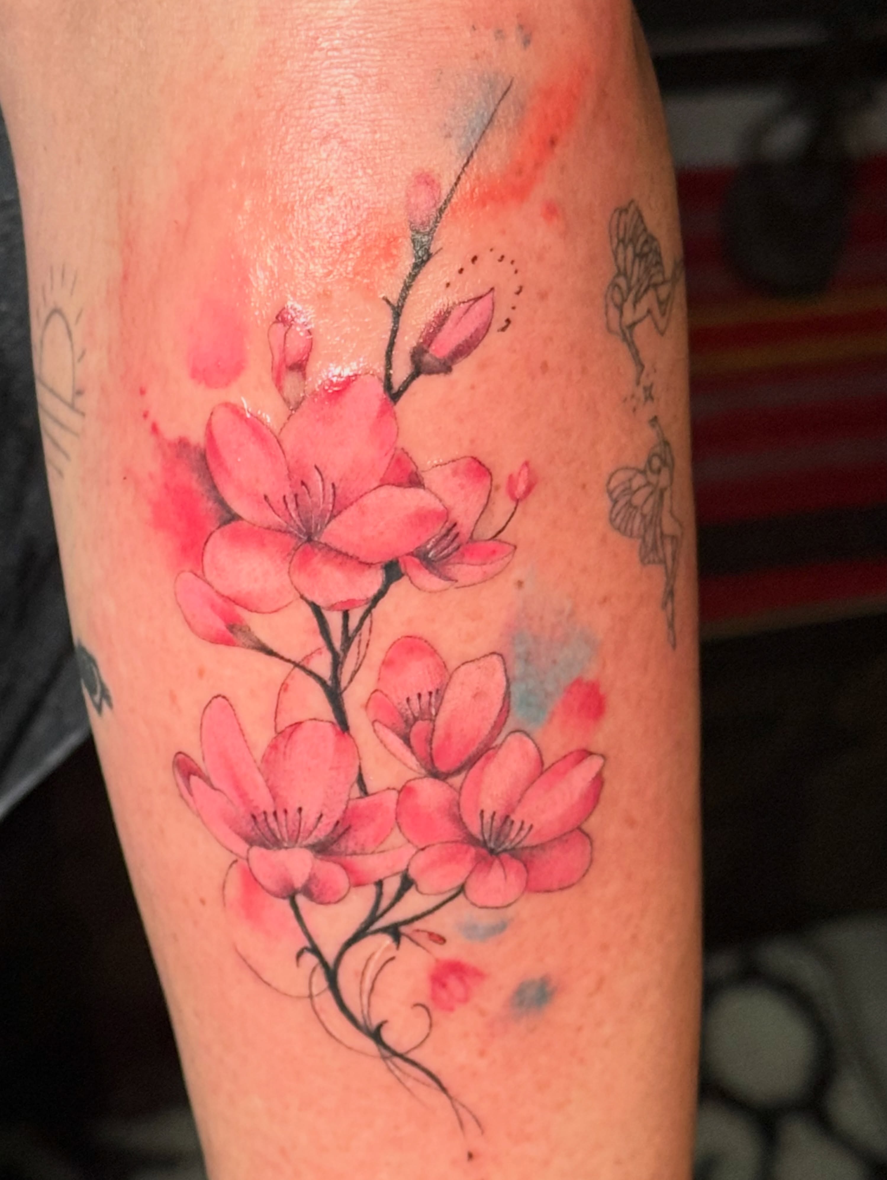 Cherry blossoms watercolor tattoo on the forearm by Faith Lopez