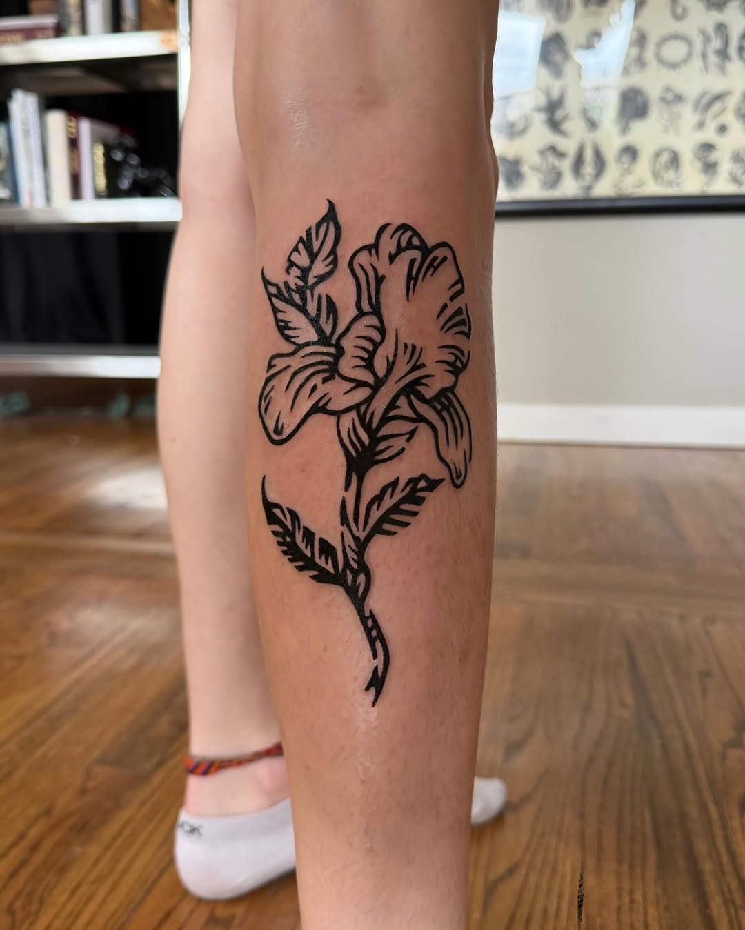 Flower fine line tattoo on the calf by M