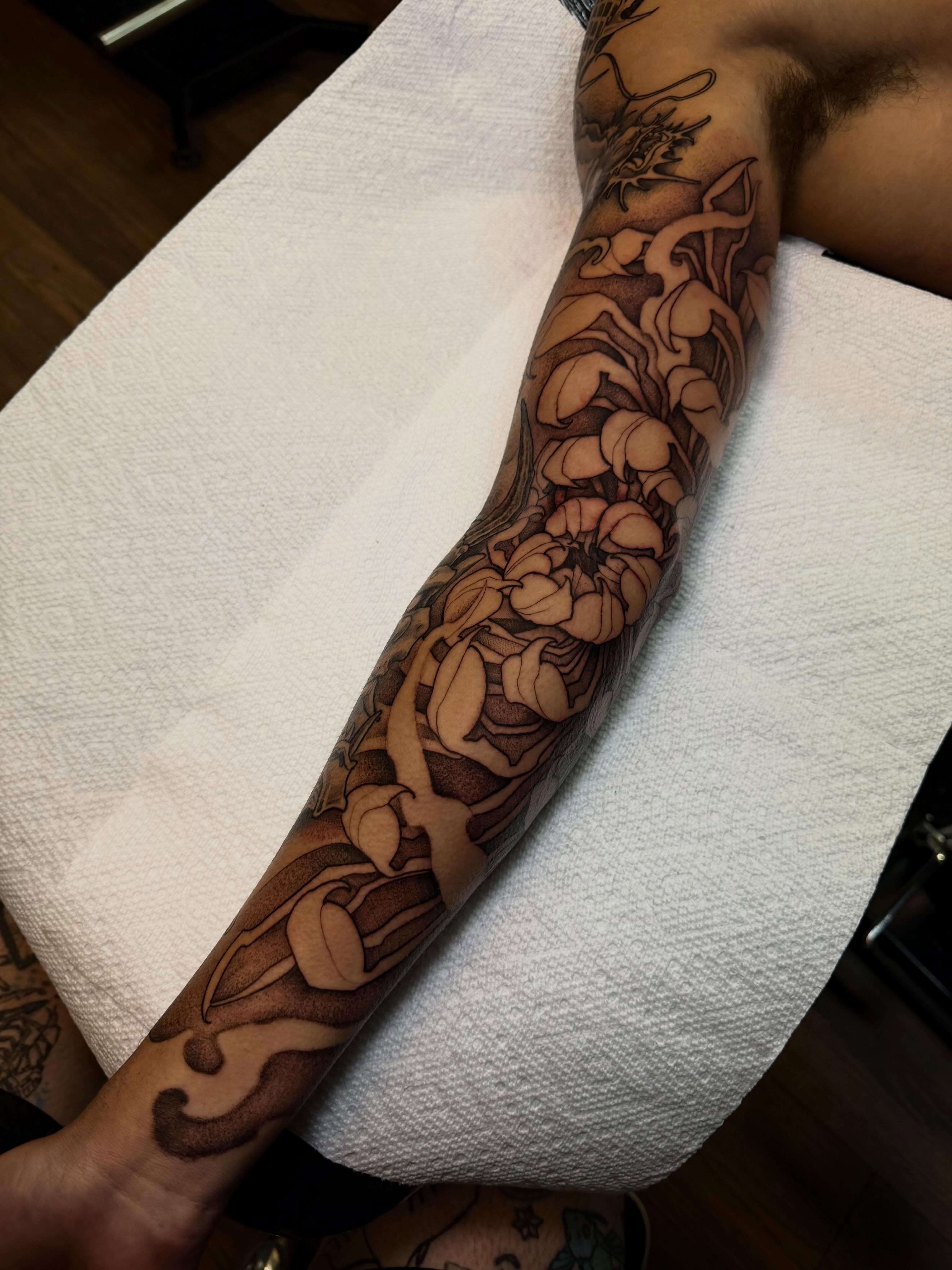 Floral pattern black and grey tattoo on the forearm by Adam Newton