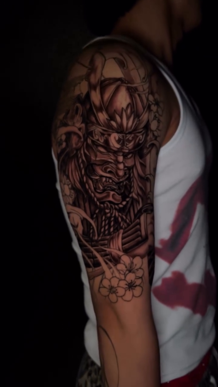 Samurai mask and floral elements Japanese tattoo on the upper arm by bev
