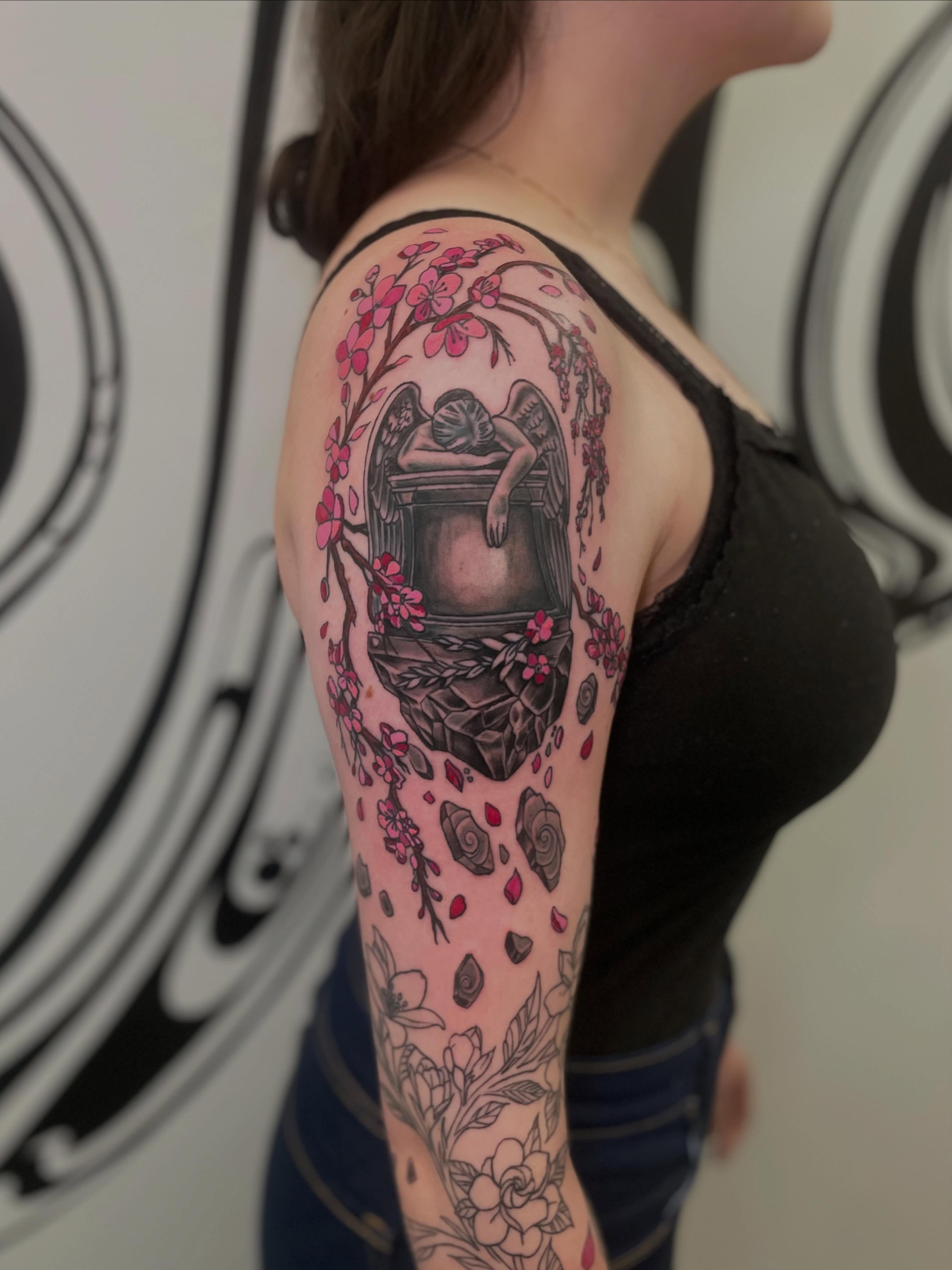 Angels and blossoms neo-traditional tattoo on the upper arm by Joey Taylor