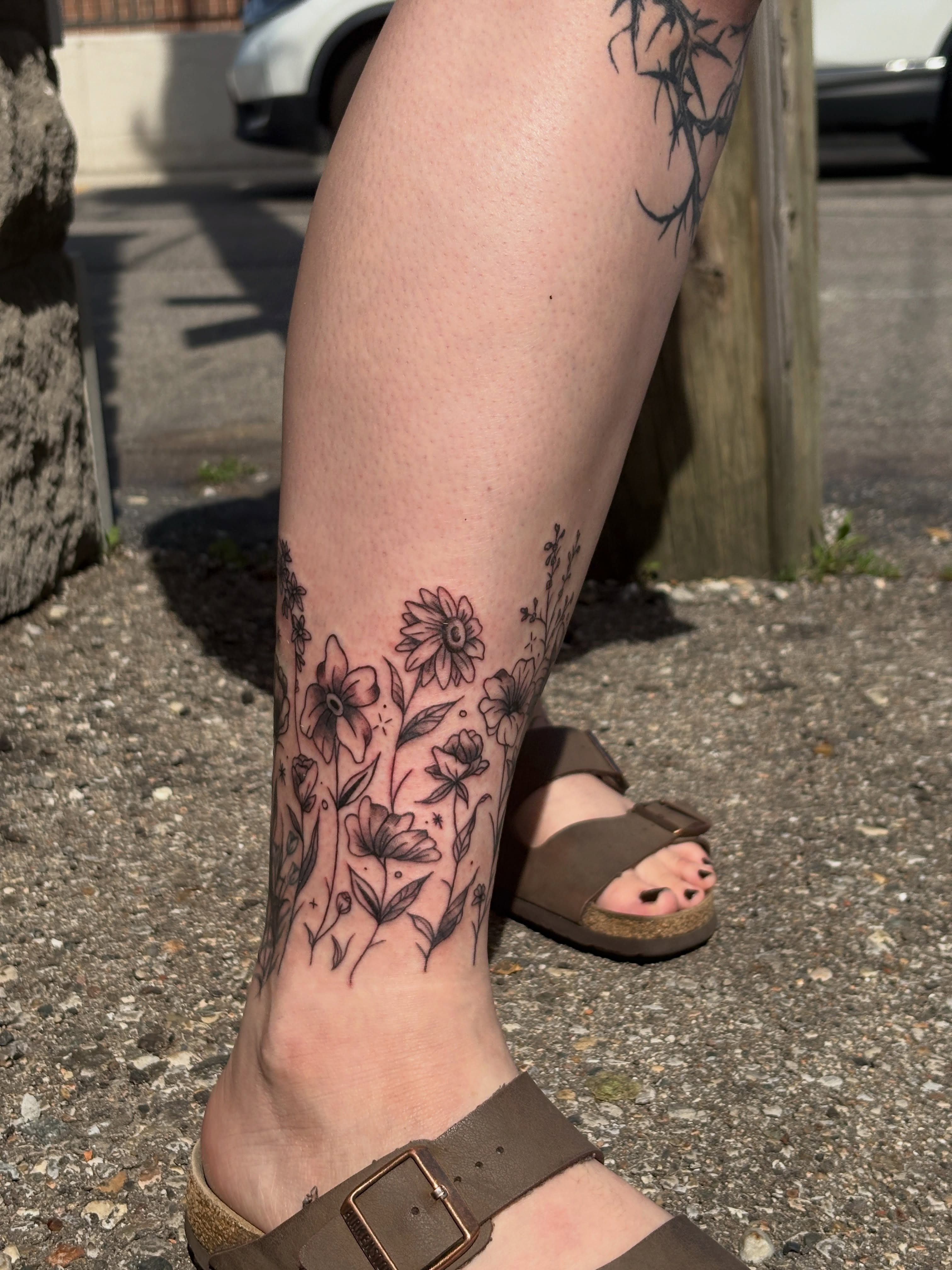 Floral bouquet black and grey tattoo on the calf by ⋆.˚ ☾ .⭒˚ alaina