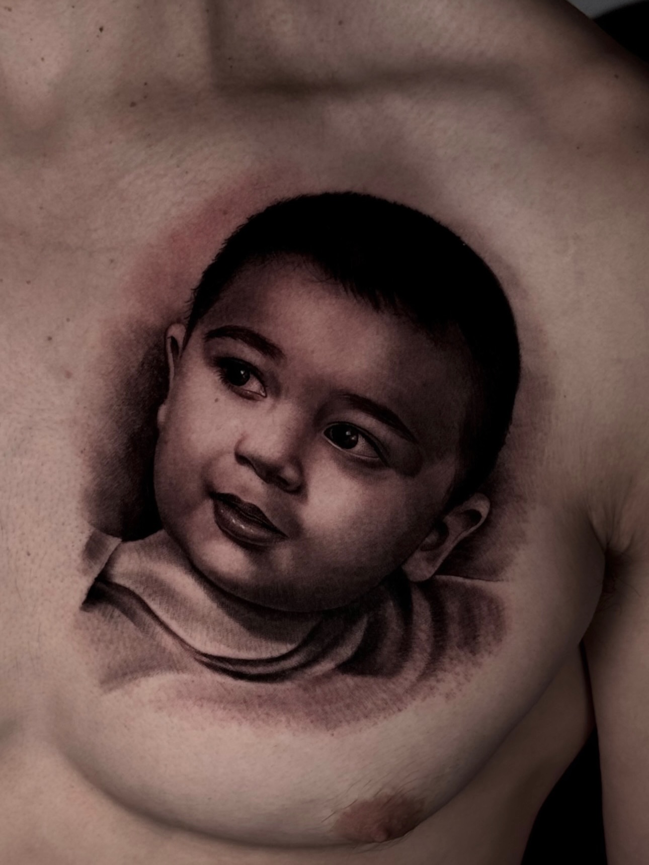 Baby portrait realism tattoo on the chest by Yudel