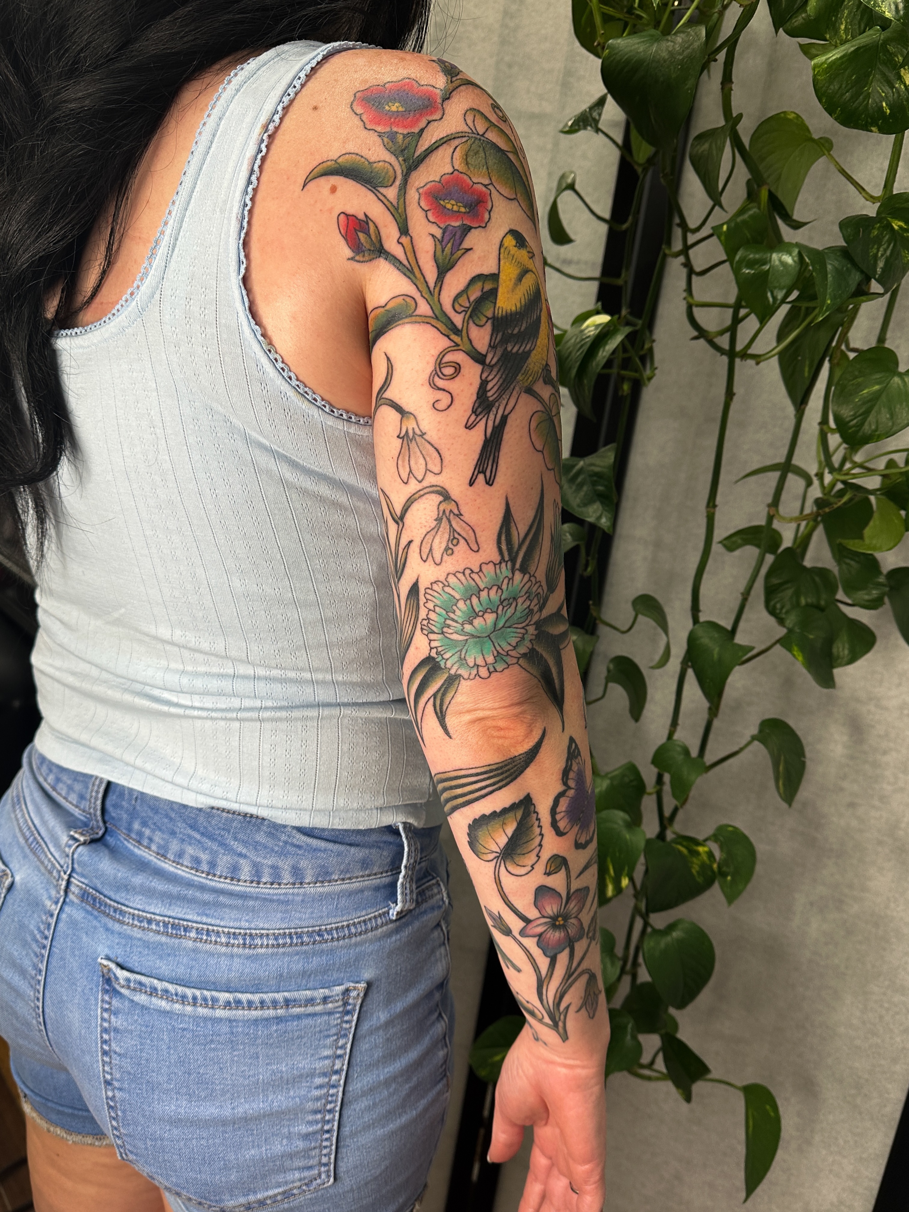 Floral and bird American traditional tattoo on the upper arm by Hannah Eddy