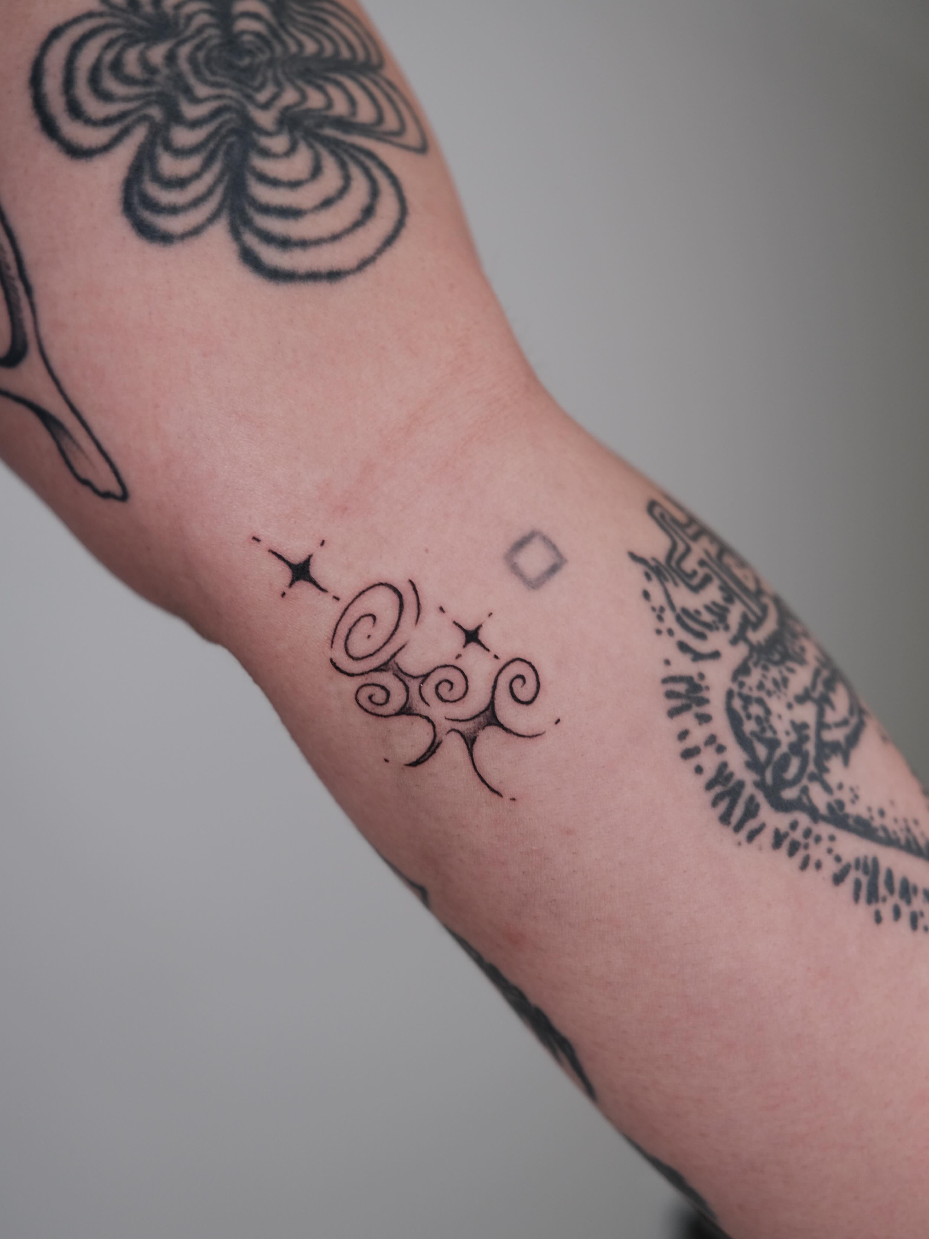 Swirls and stars fine line tattoo on the forearm by Elana Hites