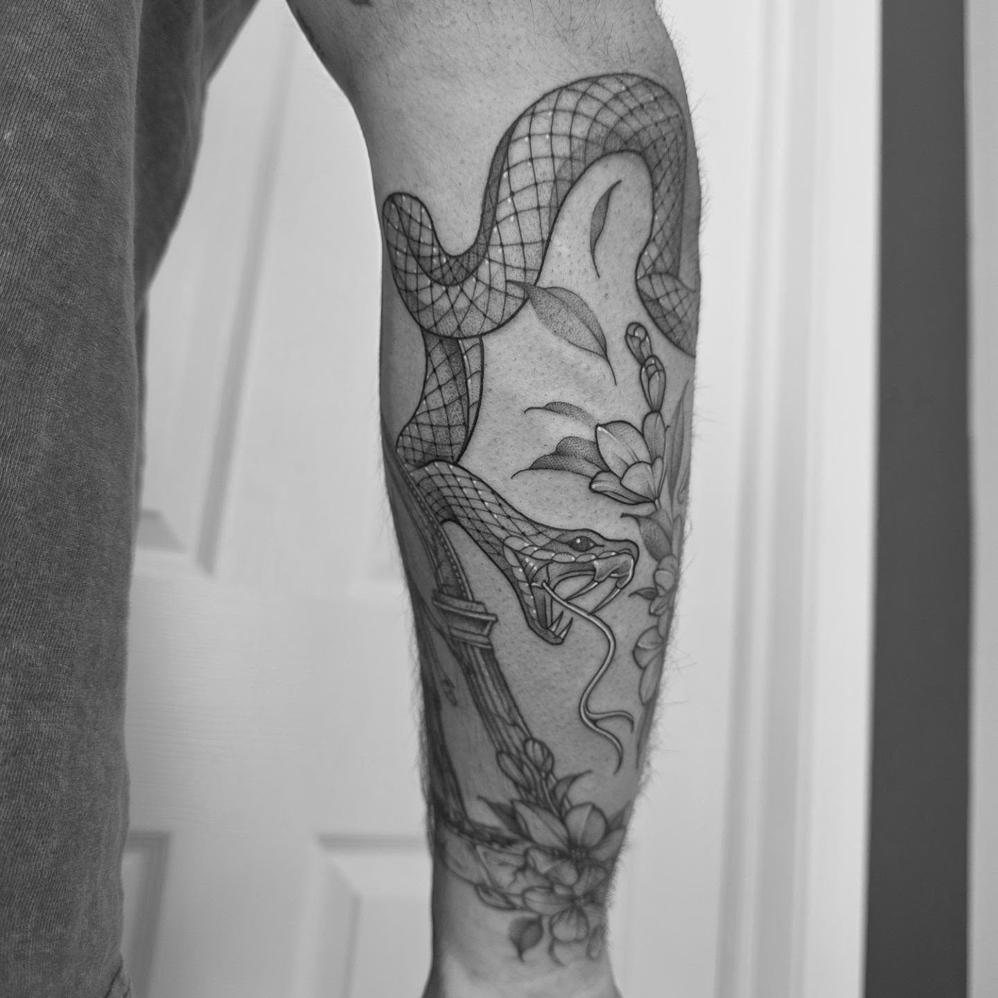 Snake and flowers geometric tattoo on the forearm by Dani Bond