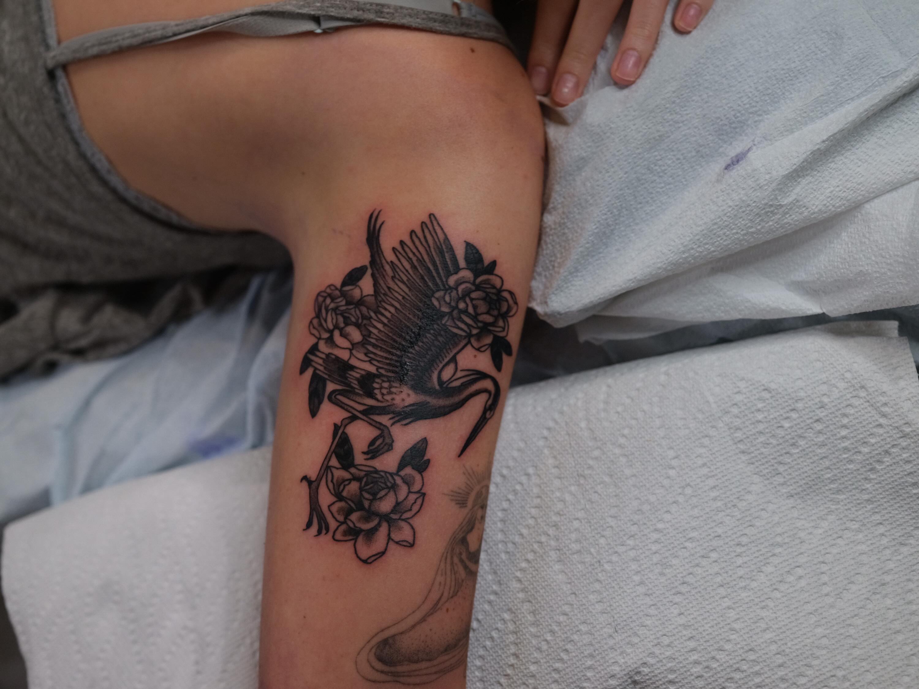 Bird and flowers black and grey tattoo on the thigh by Dylan Coverdale