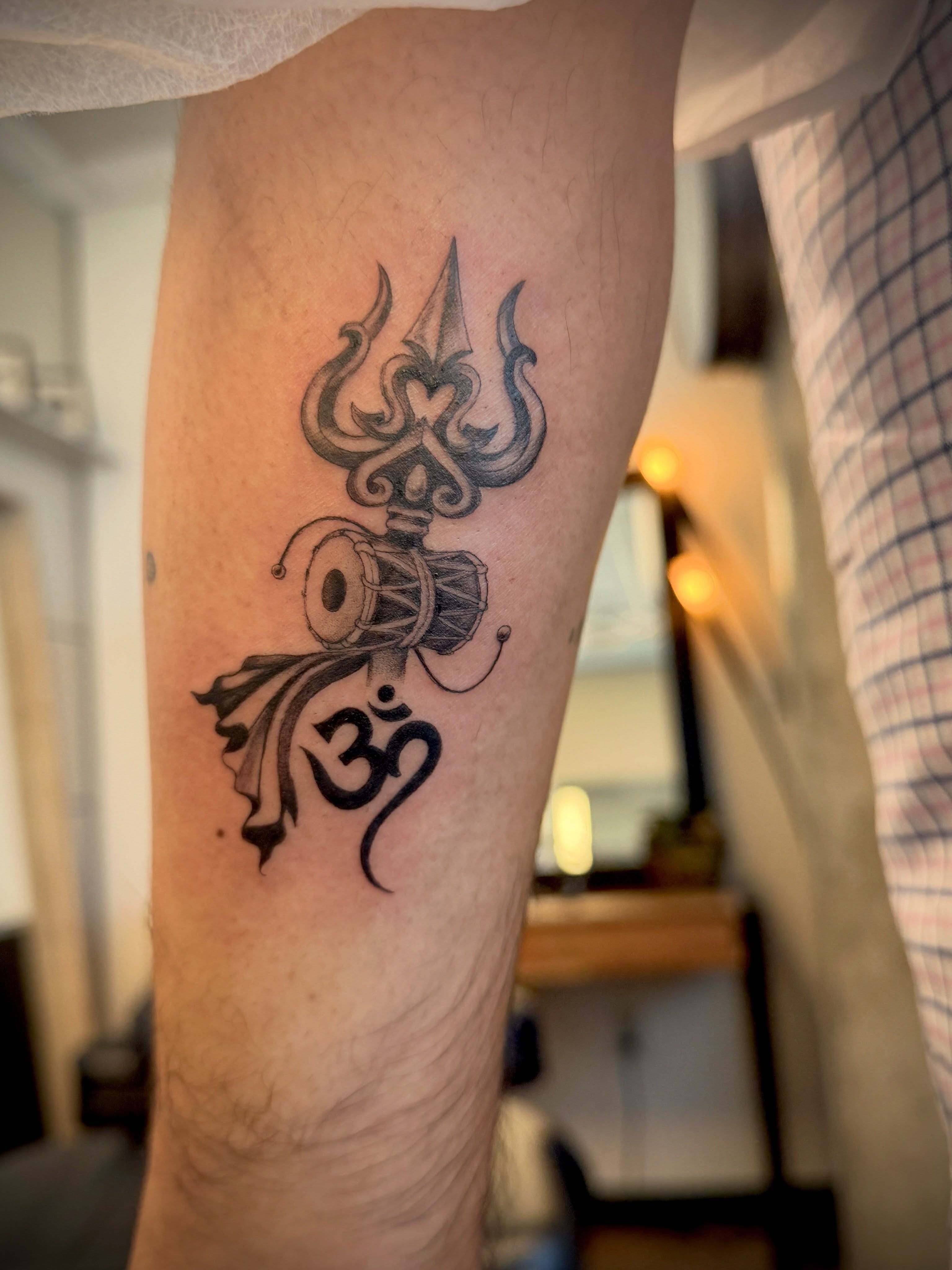 Trident and om symbol black and grey tattoo on the forearm by Aristova Anastasia