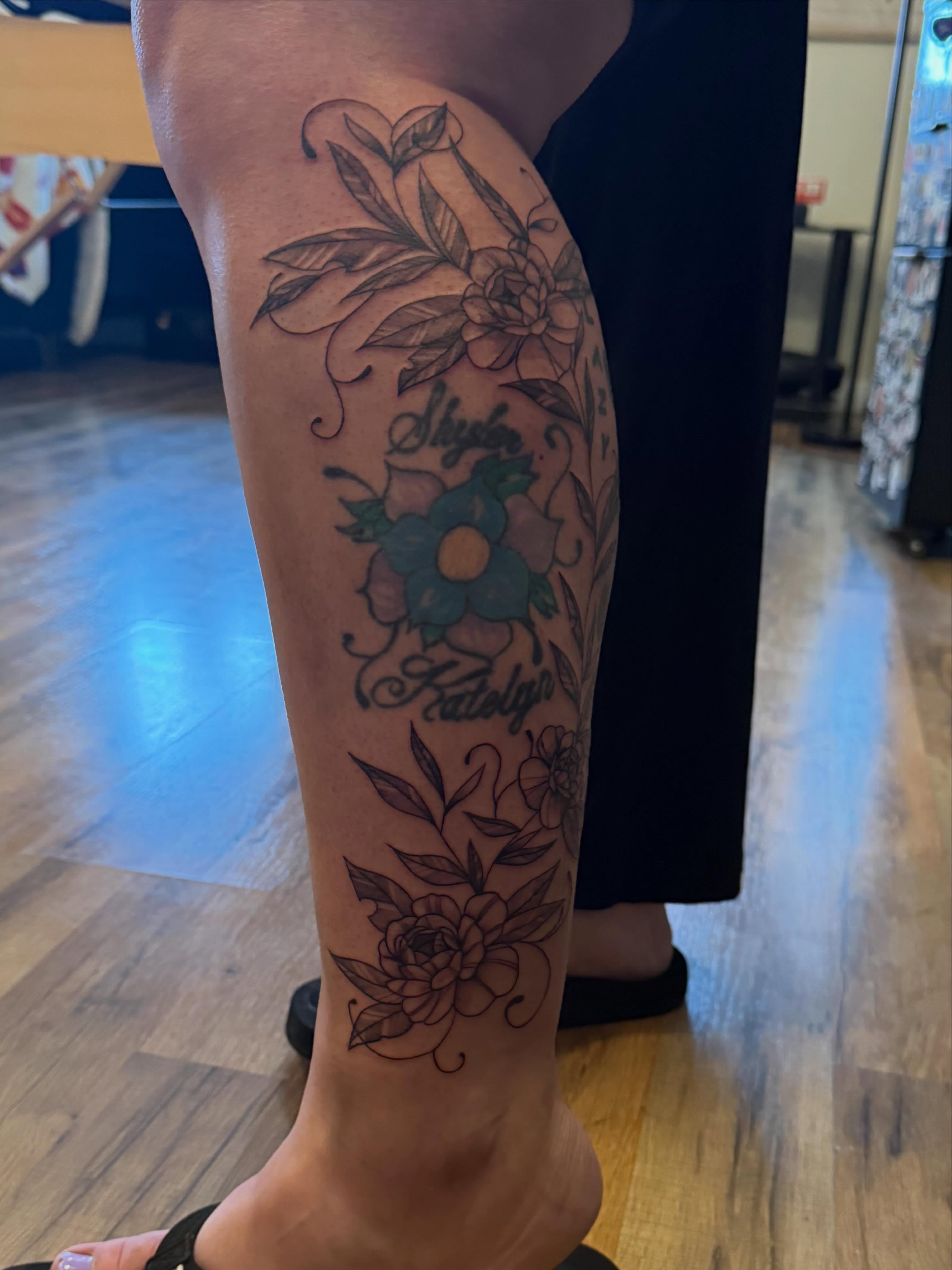 Floral arrangement black and grey tattoo on the calf by Lauren Horness