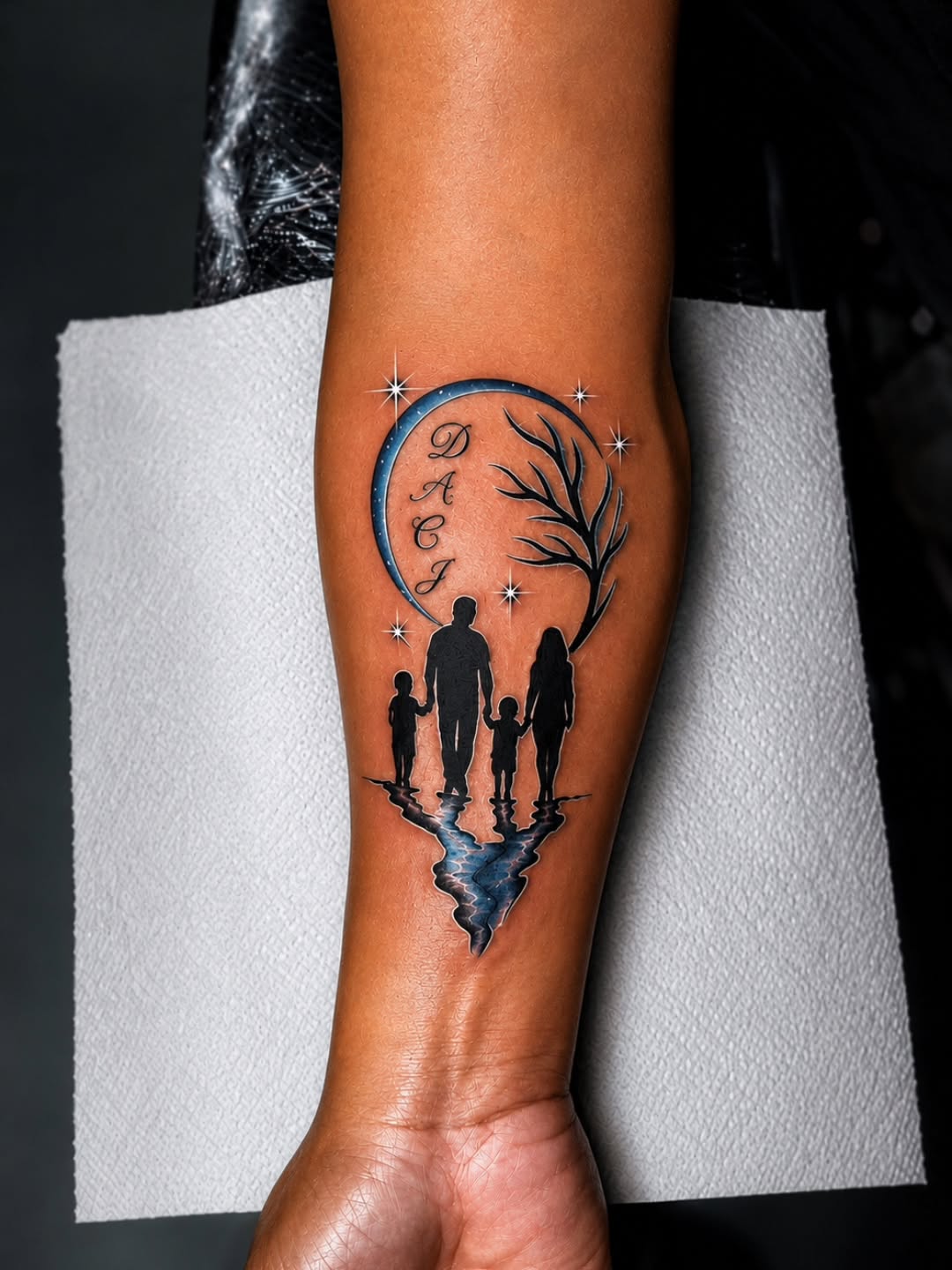 Family silhouette with moon and reflection fine line tattoo on the forearm by Kai_Tattoo