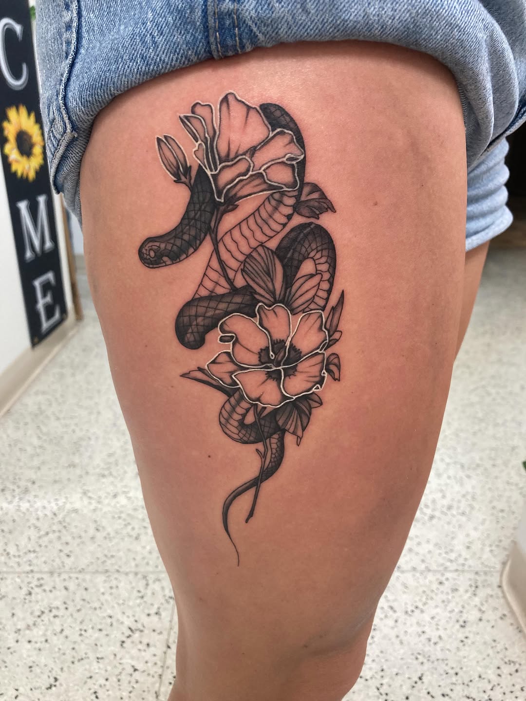 Snake and flowers realism tattoo on the thigh by Timothy Murtaugh
