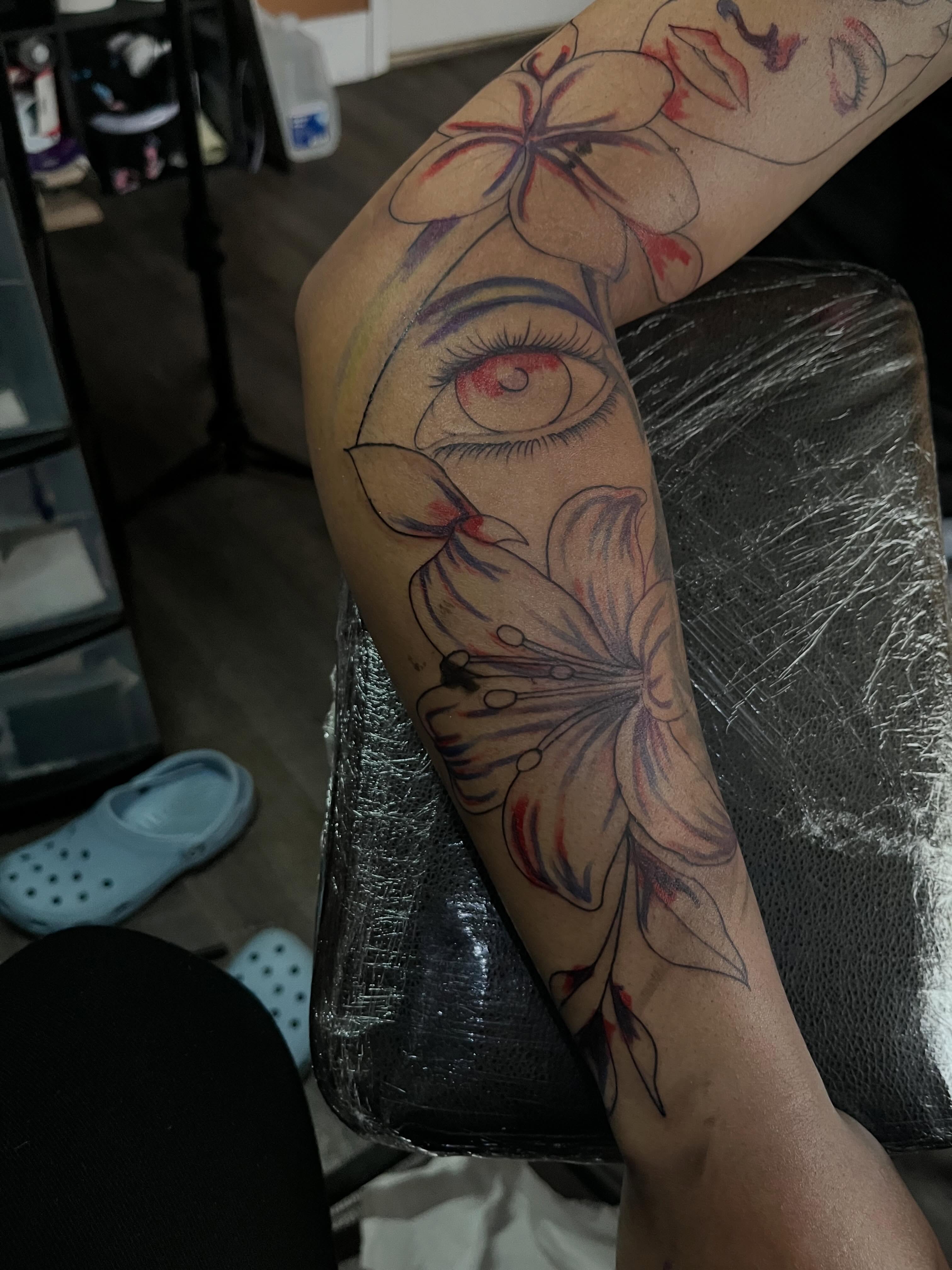 Eye and flowers realism tattoo on the forearm by Tam💟👩🏽‍🎨