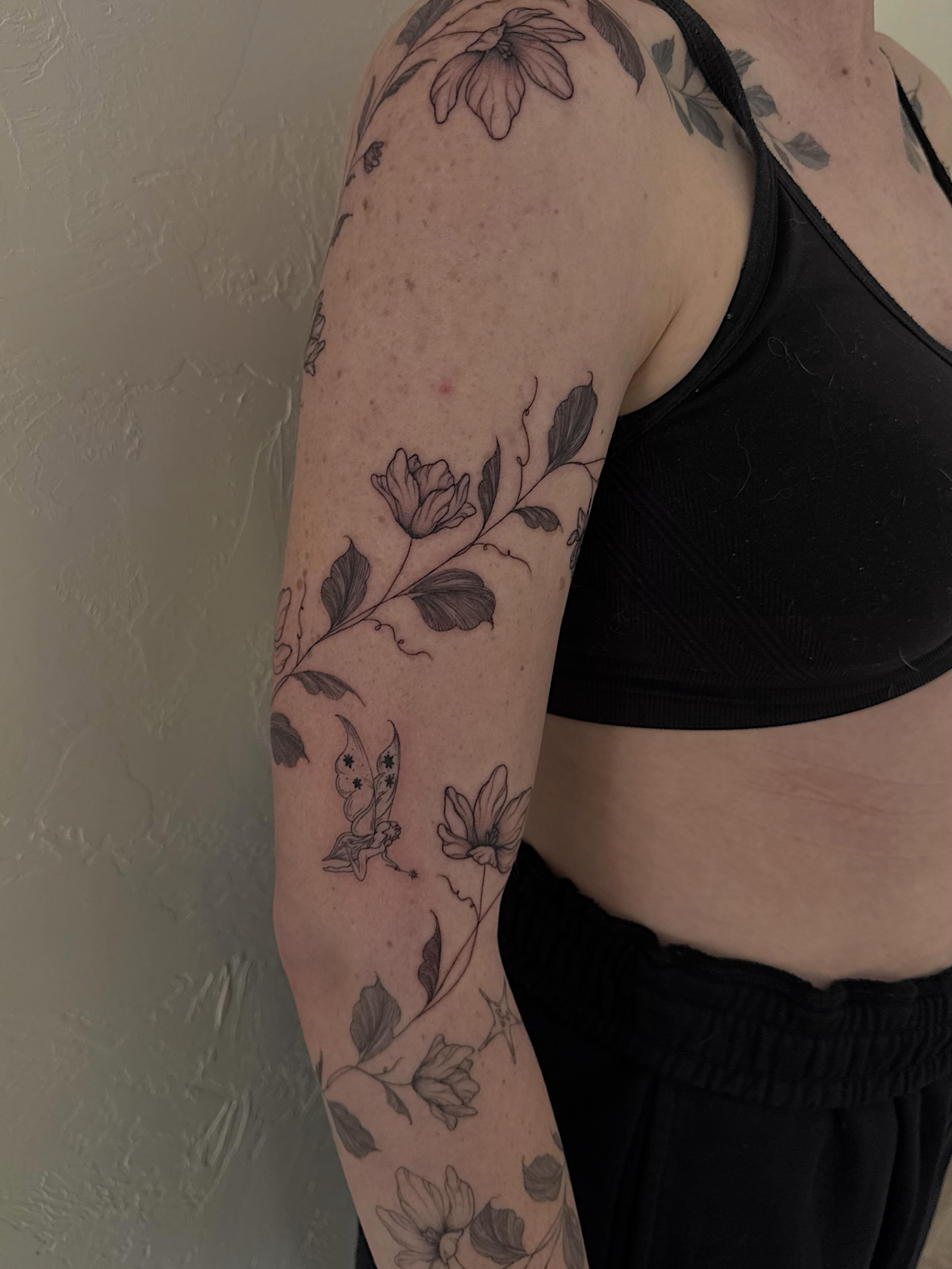 Floral vine with fairy fine line tattoo on the upper arm by Shelby Lynn Bayles, Ogden, Utah