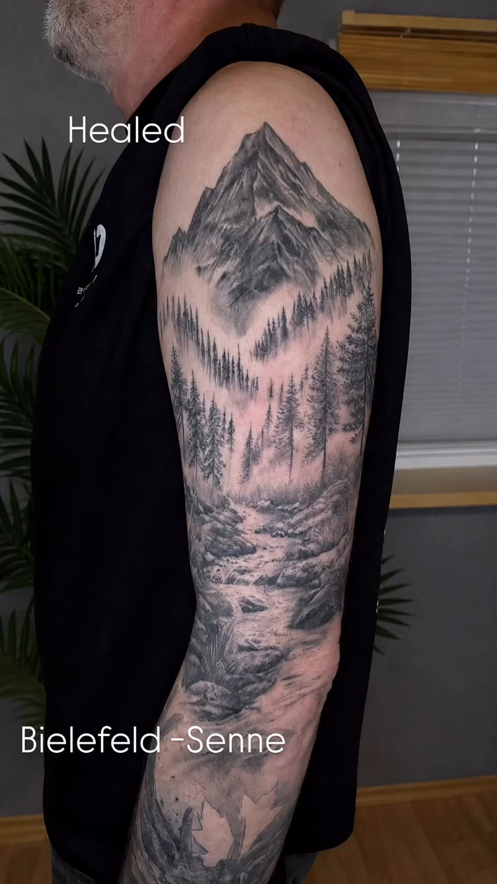 Mountain landscape with trees fine line tattoo on the upper arm by Die Ivo, Bielefeld, Germany
