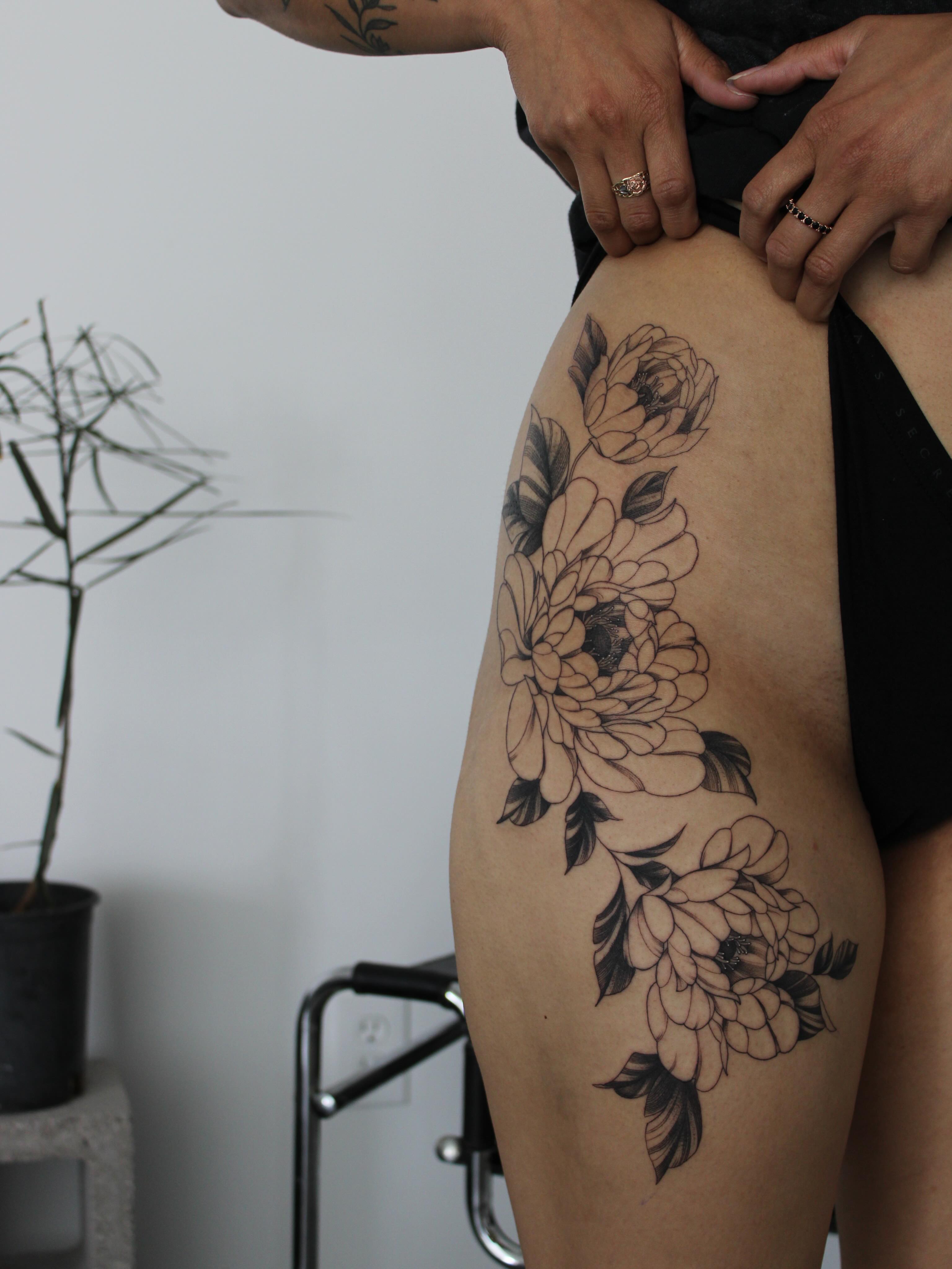 Floral arrangement black and grey tattoo on the thigh by Julianna