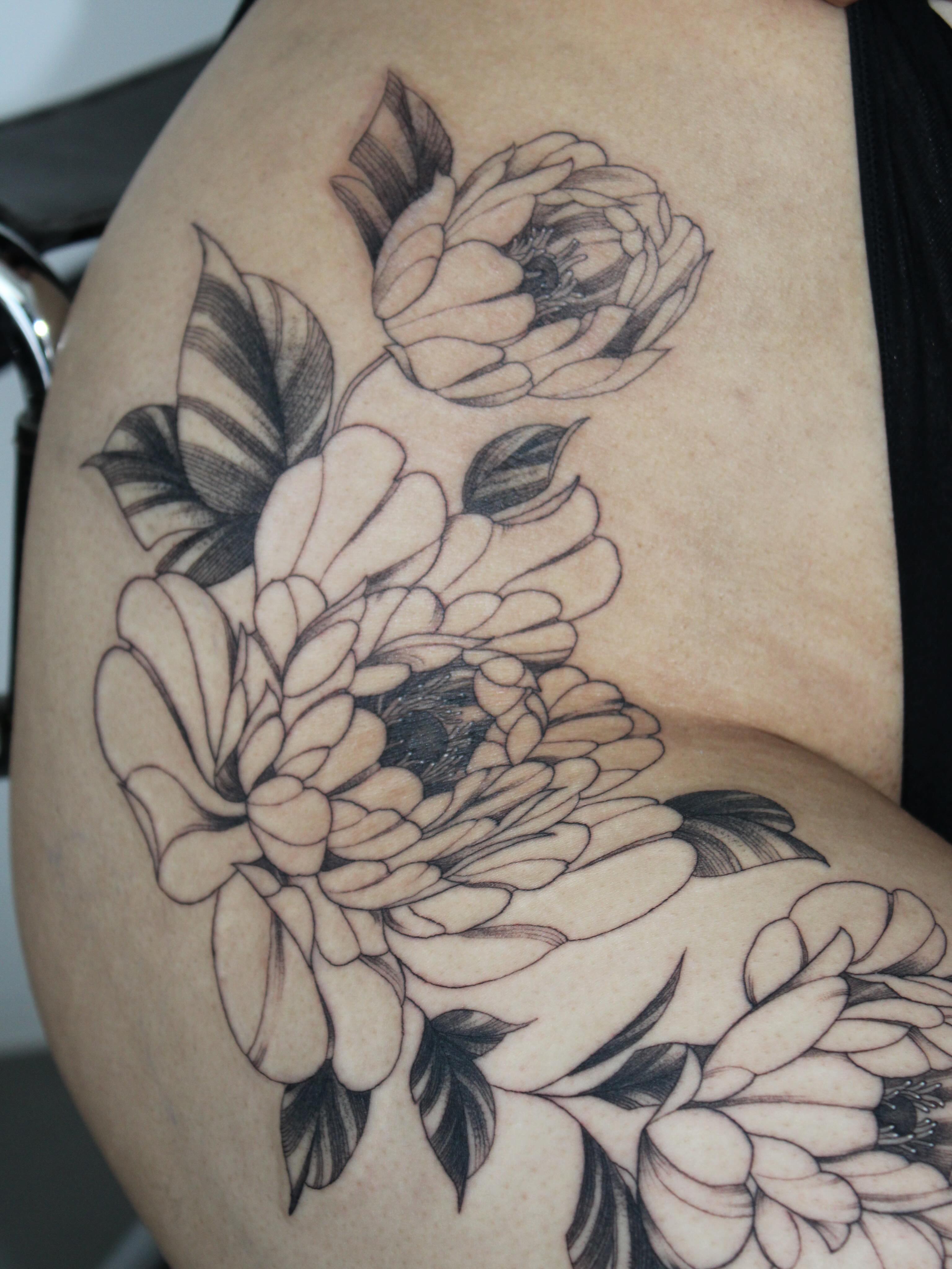 Floral arrangement black and grey tattoo on the thigh by Julianna