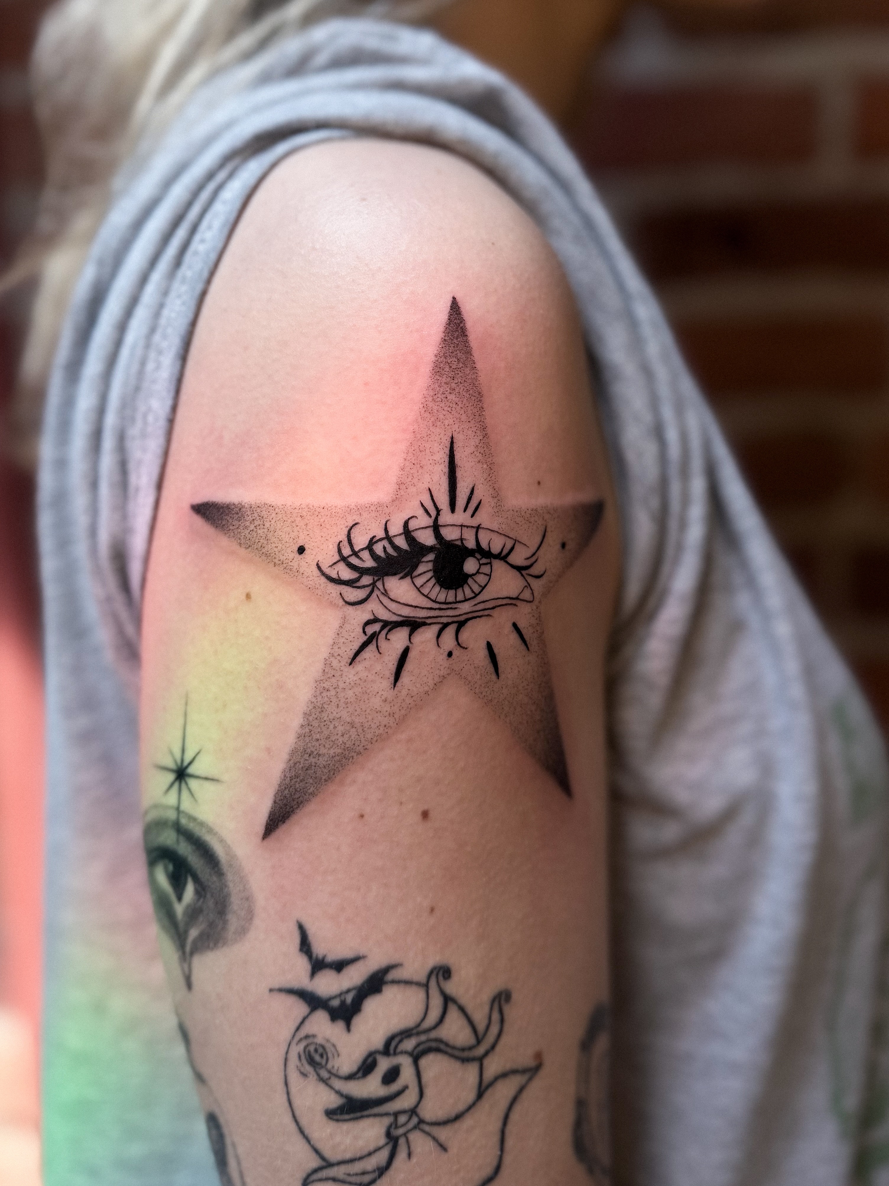 Eye within star black and grey tattoo on the shoulder by Jessica Bloom