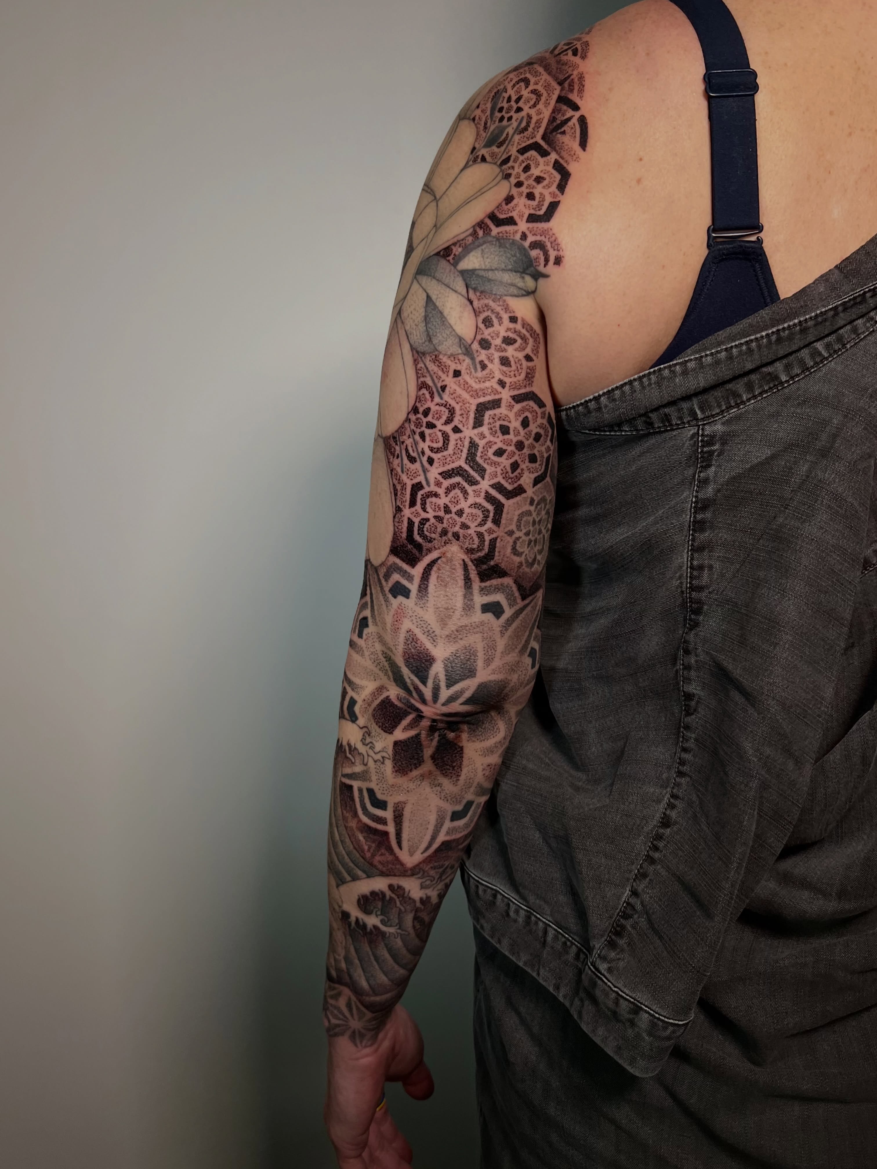 Lotus flower geometric tattoo on the upper arm by Riley