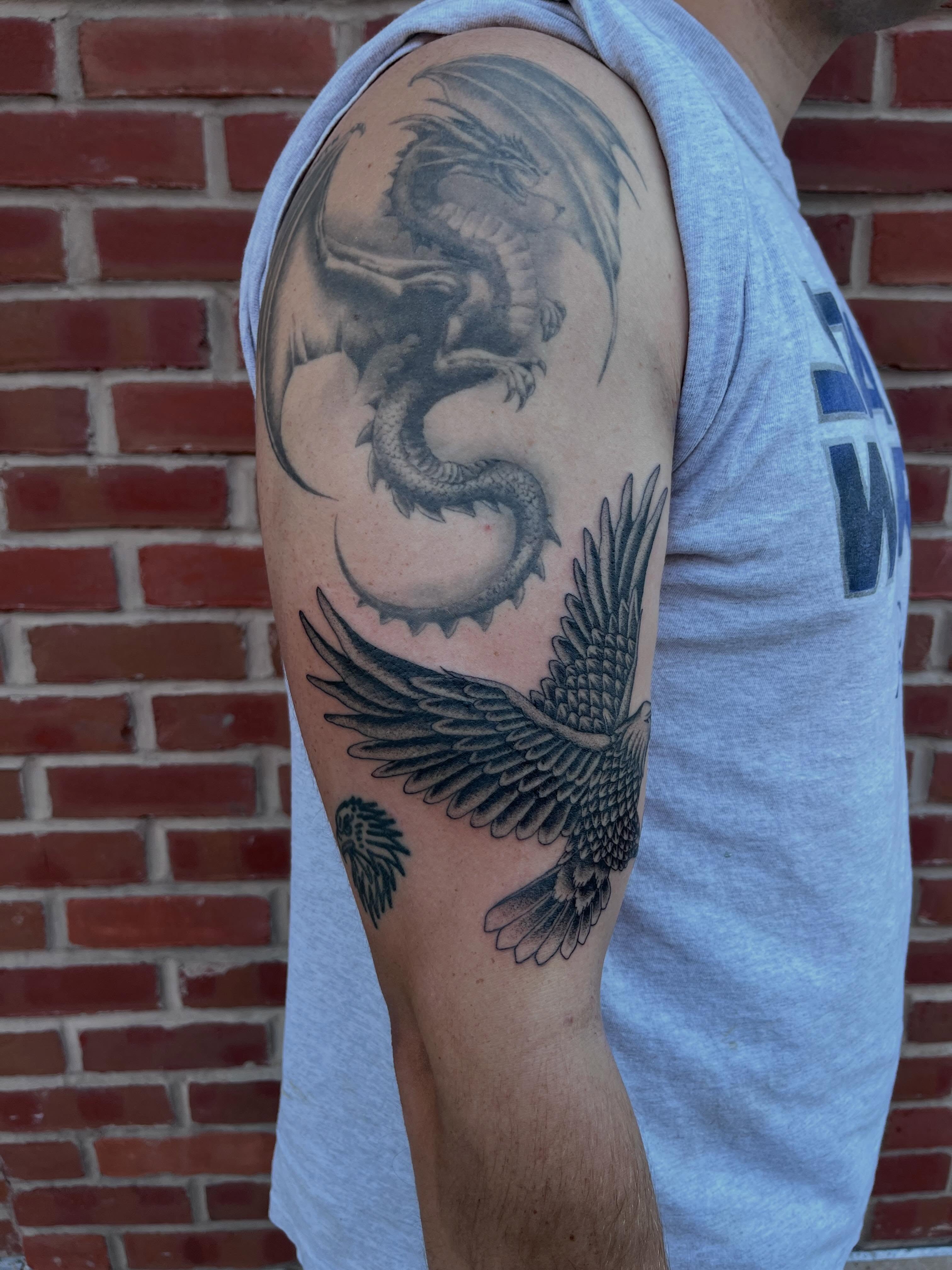 Dragon and eagle black and grey tattoo on the upper arm by Jackson Kirchhoff