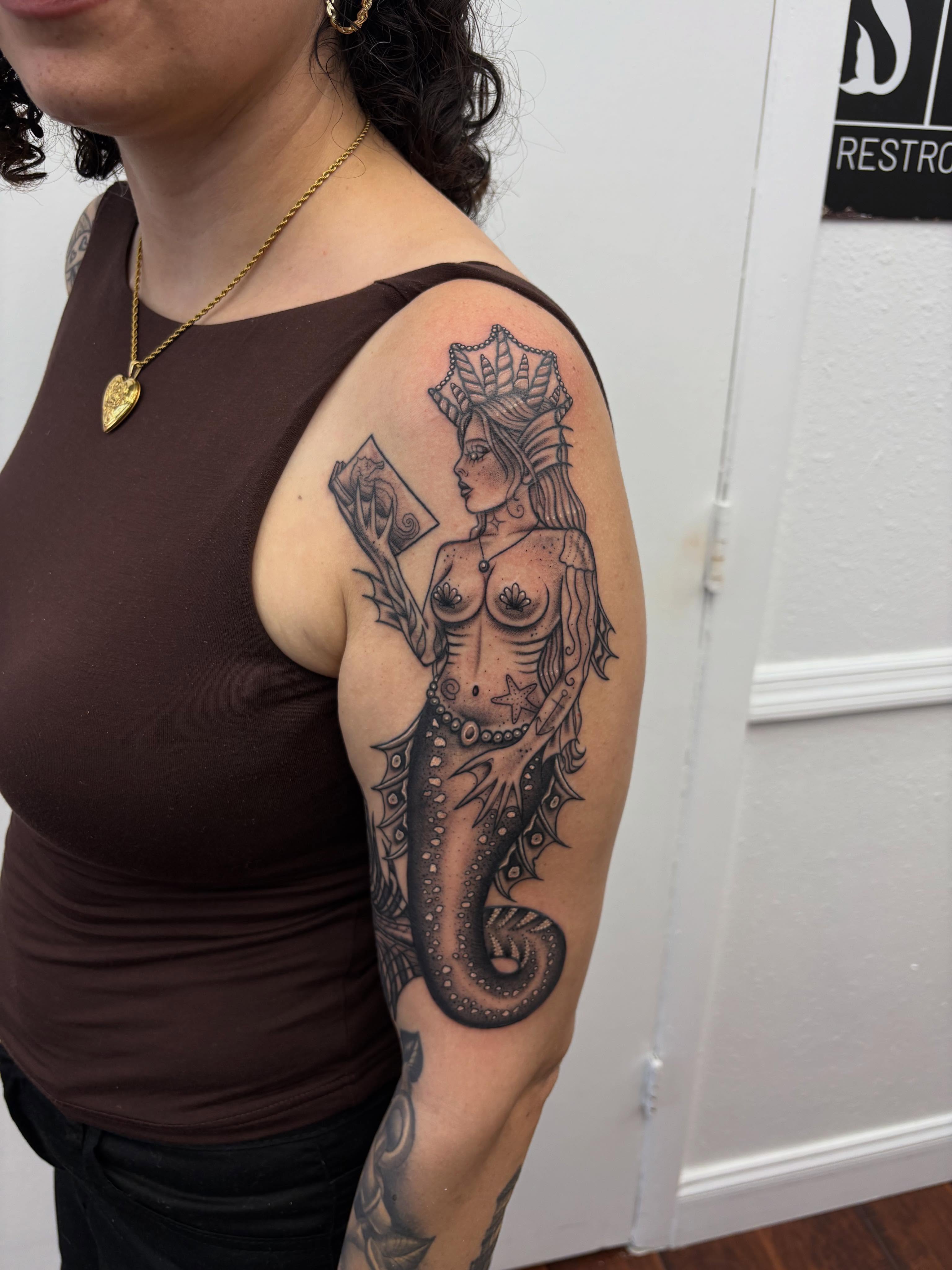 Mermaid black and grey tattoo on the upper arm by Skye California