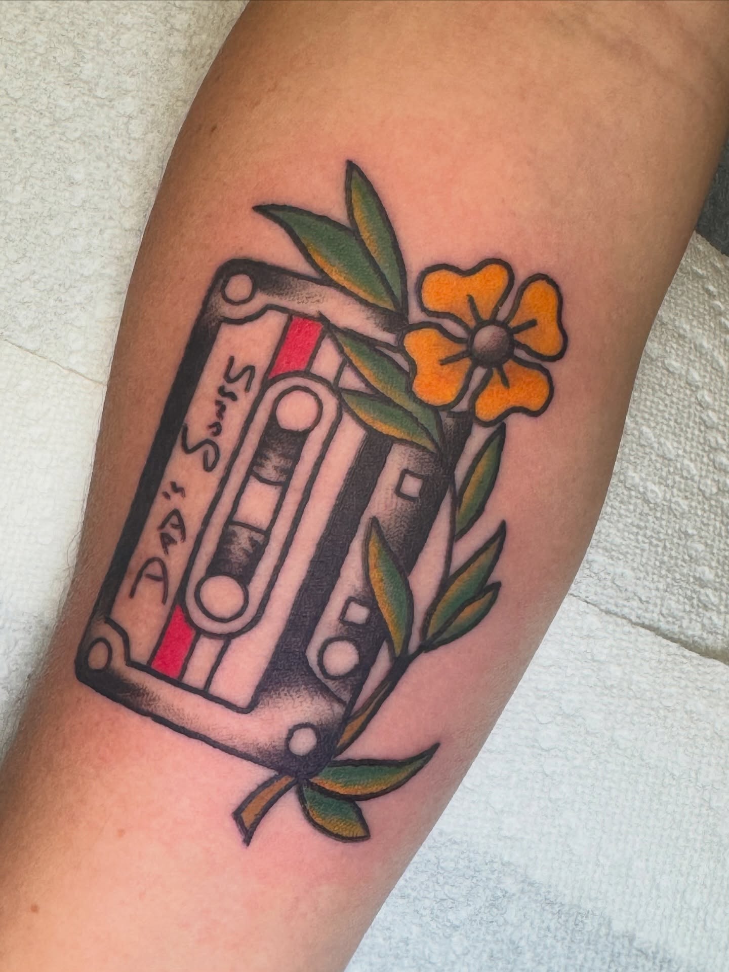 Cassette tape and flower American traditional tattoo on the forearm by Kenneth Gibson