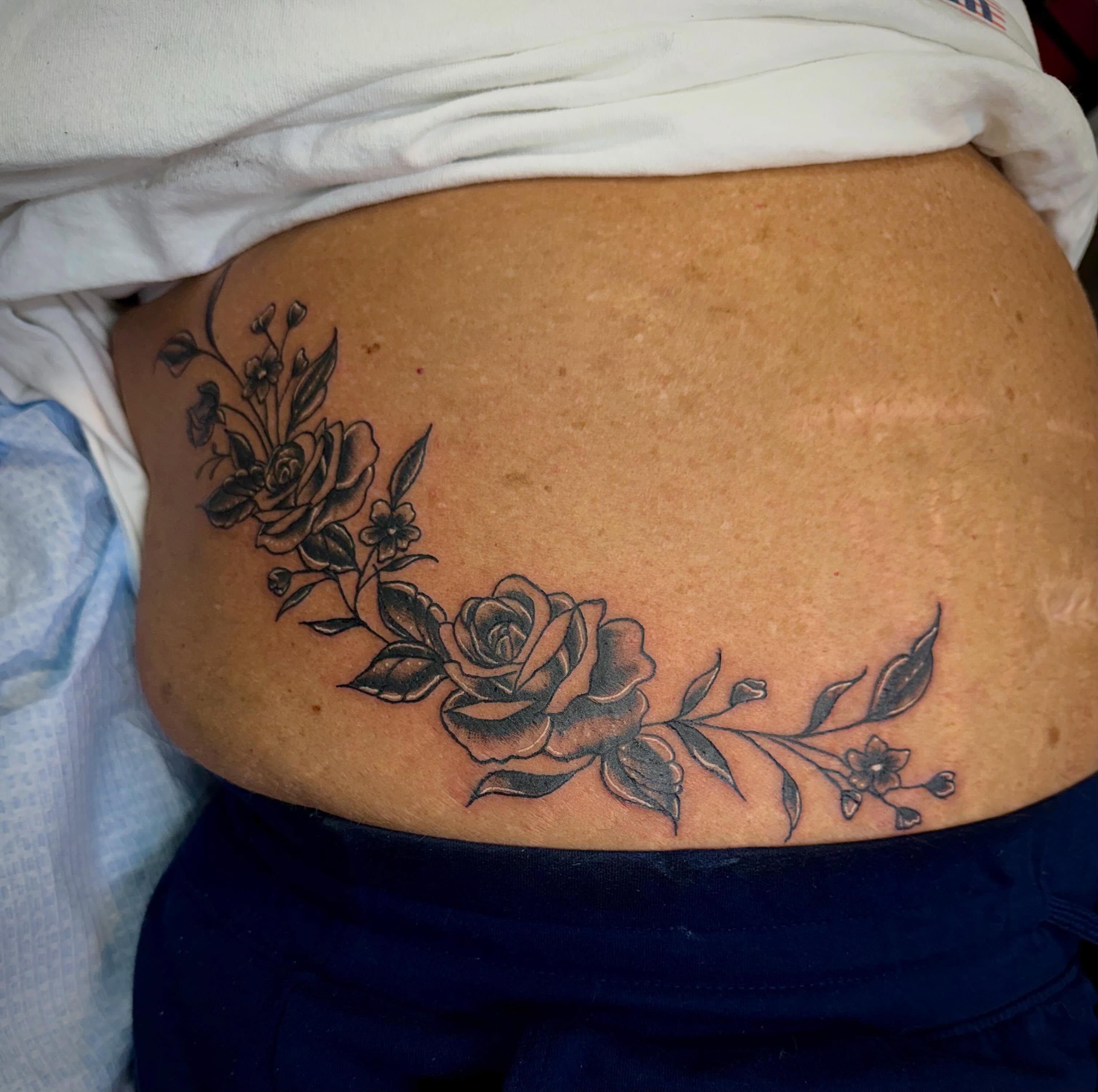 Floral design black and grey tattoo on the torso by Abigail Lewis