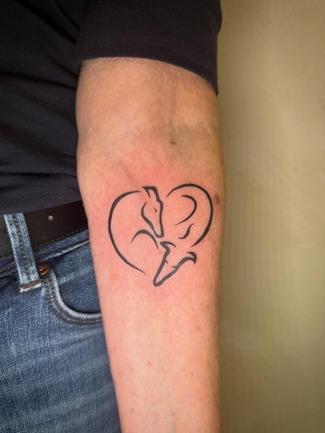 Two foxes in a heart fine line tattoo on the forearm by Danny Garcia