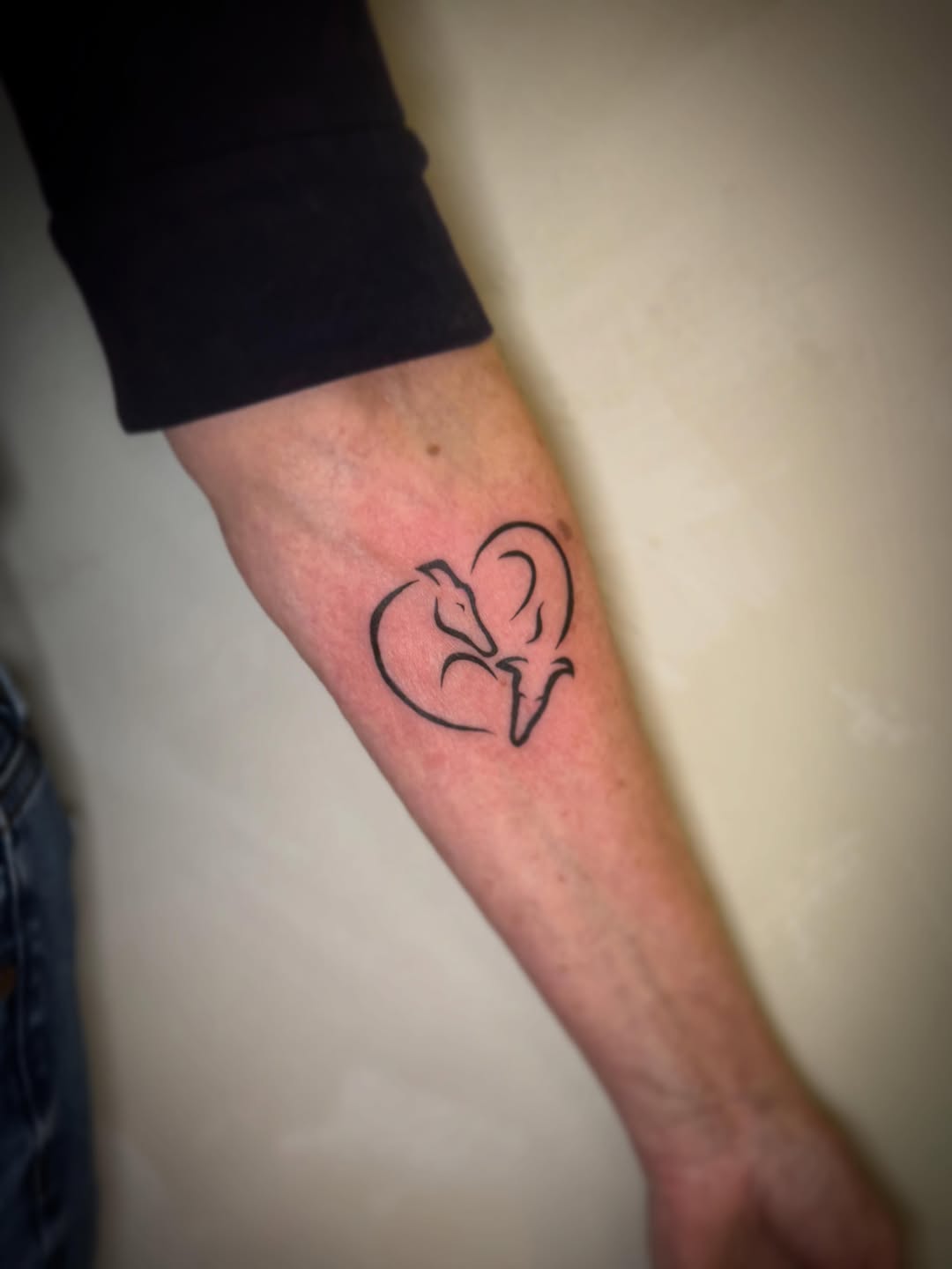 Heart with animal silhouette fine line tattoo on the forearm by Danny Garcia
