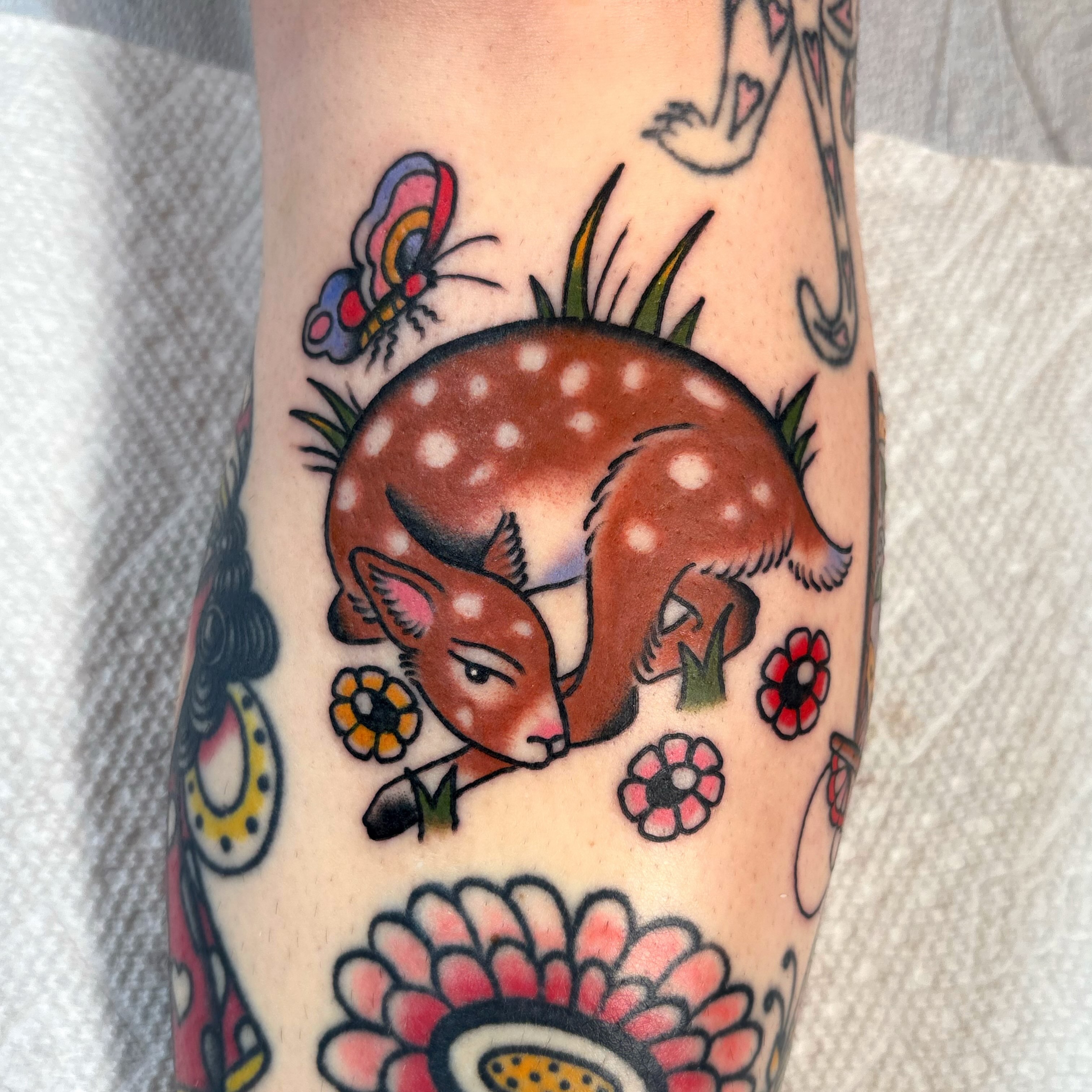 Deer and flowers American traditional tattoo on the forearm by Caeli Martin