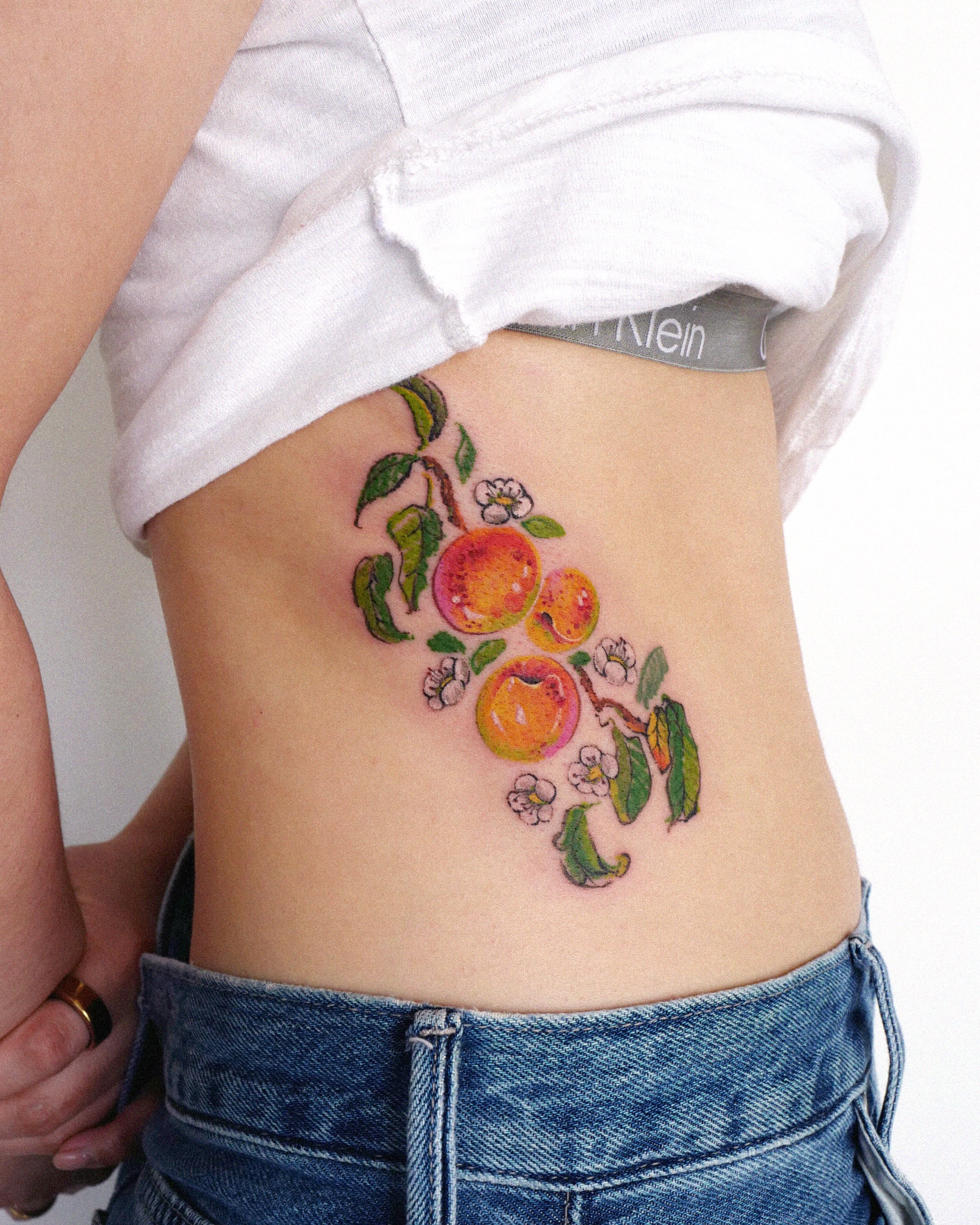 Peaches and blossoms watercolor tattoo on the ribs by dahye lee
