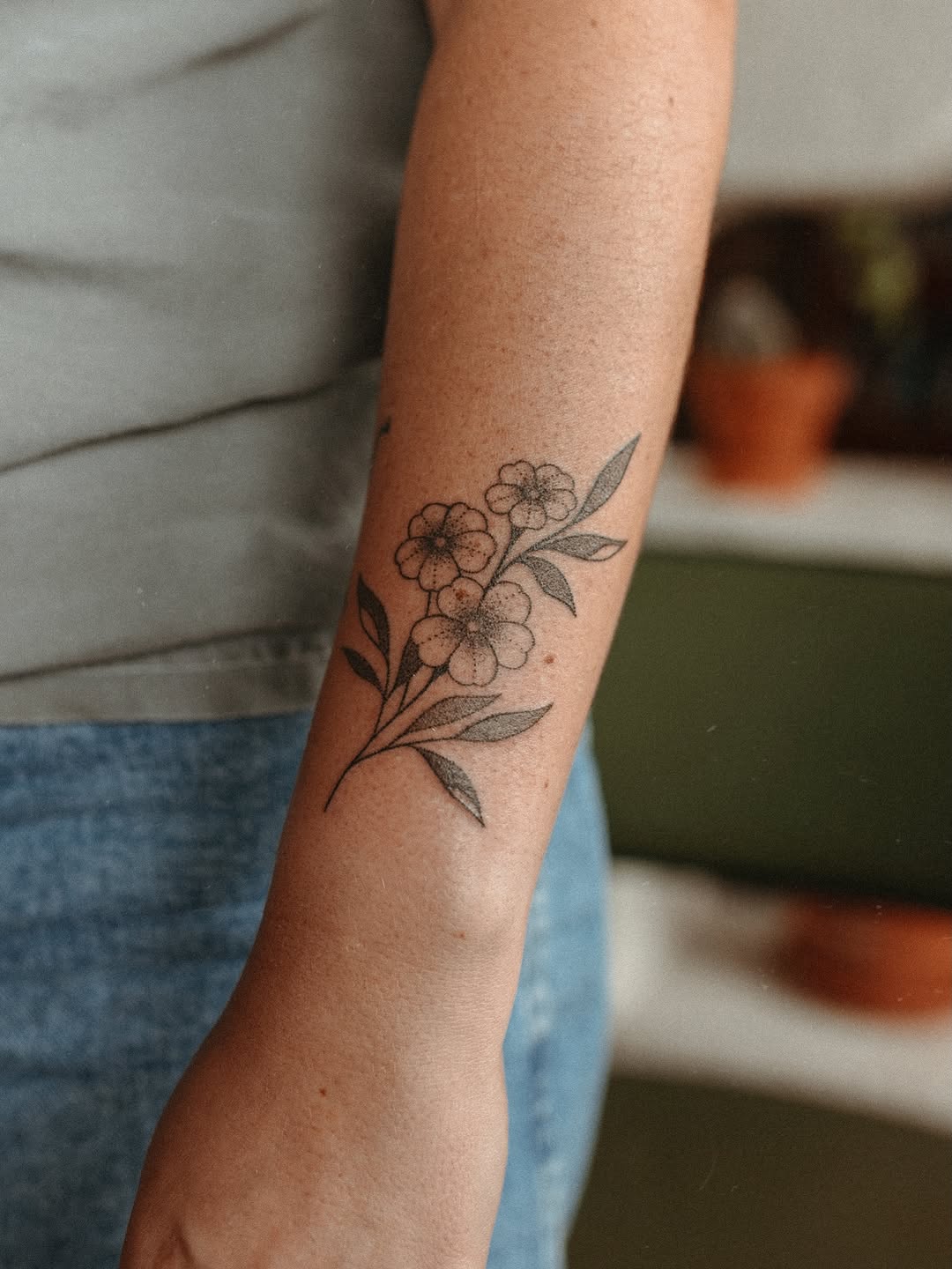 Floral branch fine line tattoo on the forearm by Grace Wise - Handpoke Tattoos