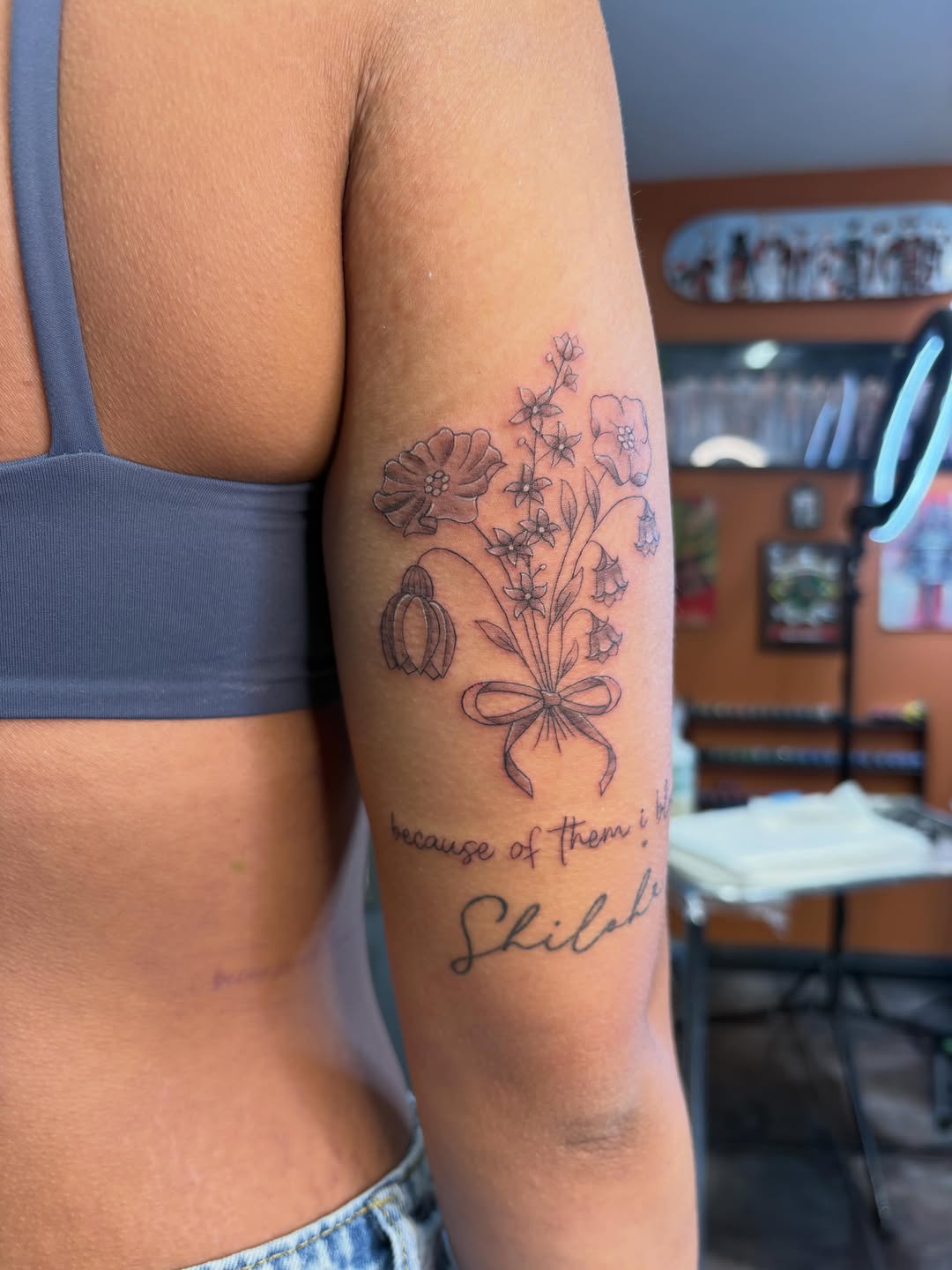Floral bouquet with script lettering fine line tattoo on the forearm by alana khounmeuang
